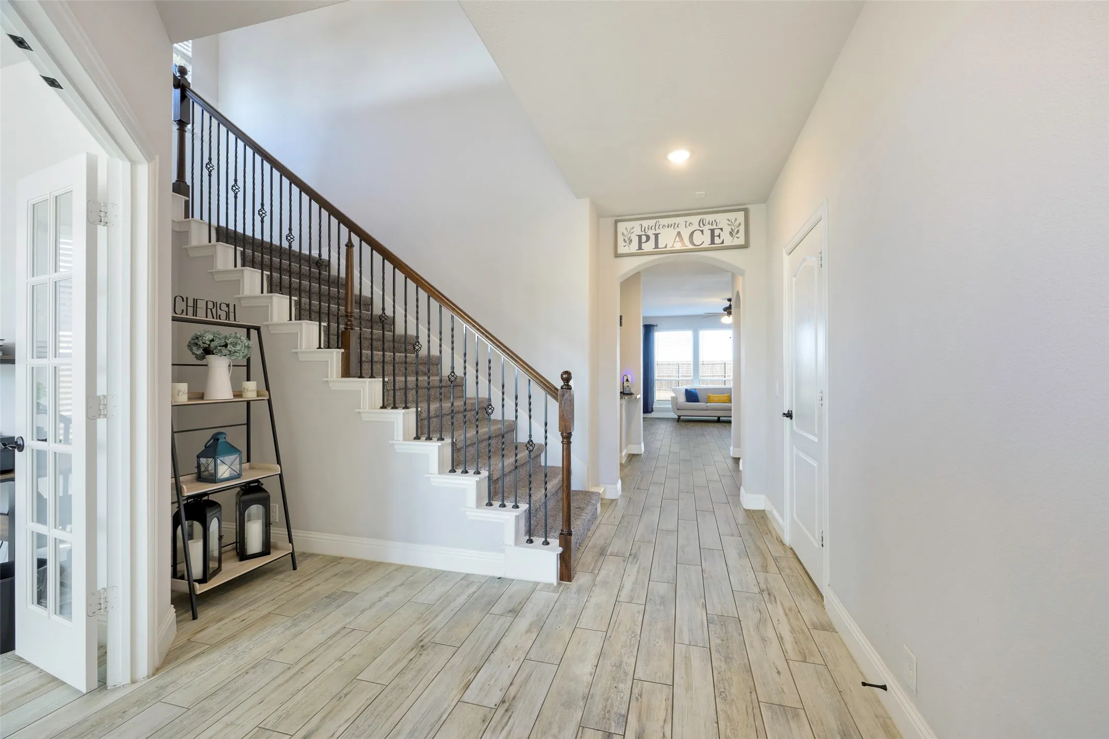 Foyer with stairs, light wood-style floors, and arched walkways