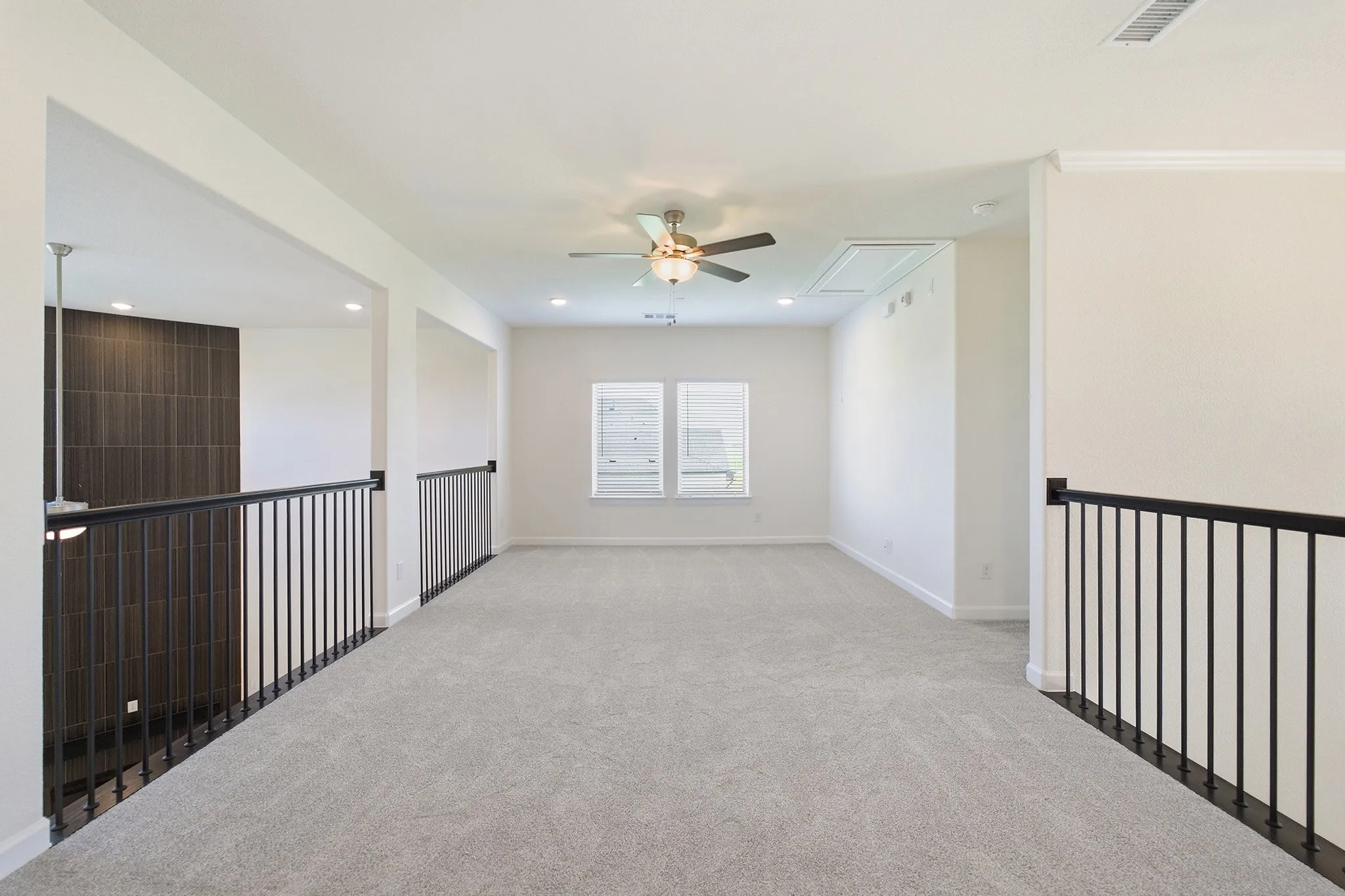 Spacious loft area featuring light gray carpet, multiple windows, recessed lighting, and a ceiling fan