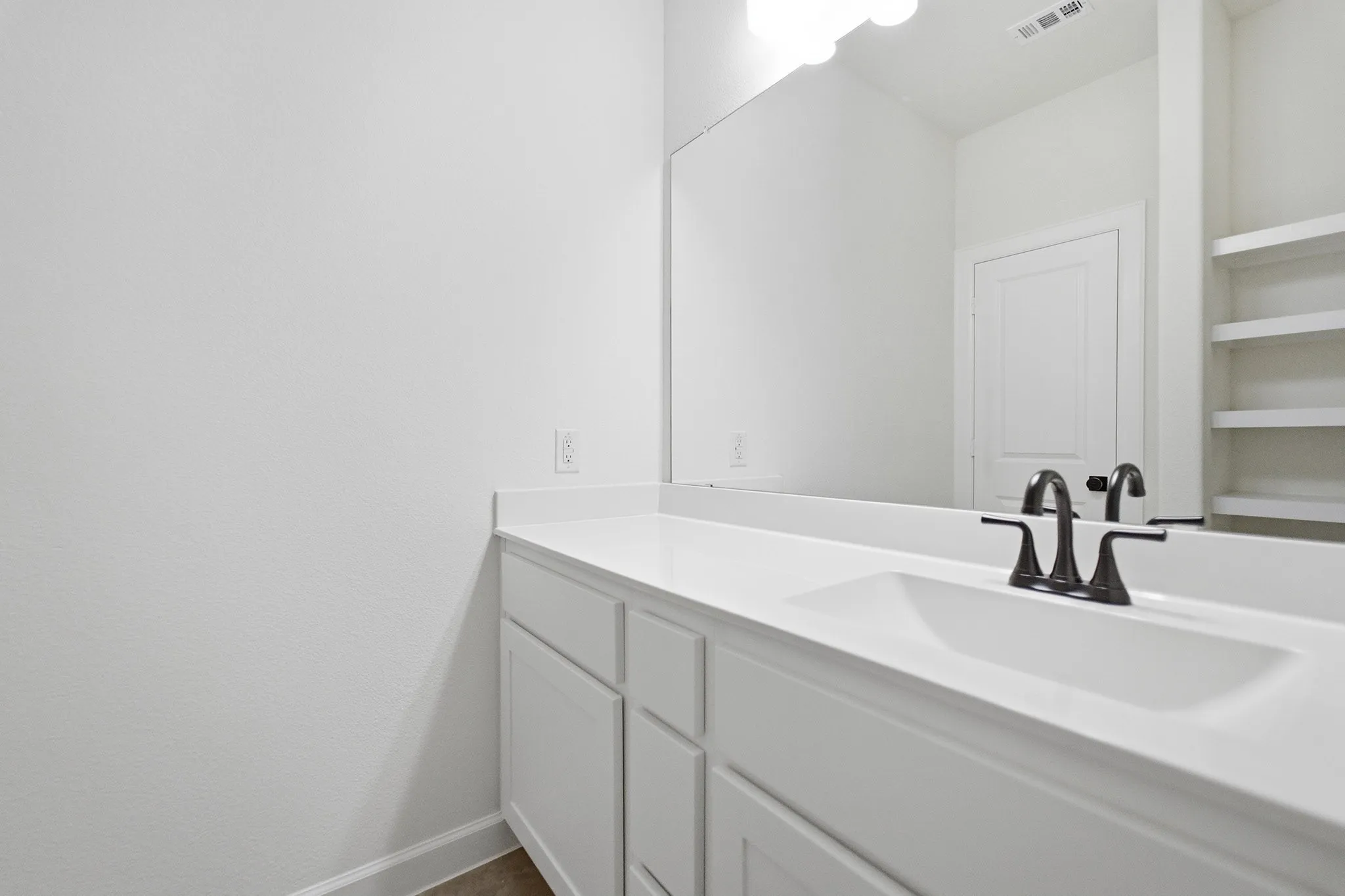 Vanity featuring a white countertop, integrated sink, and dark bronze faucet