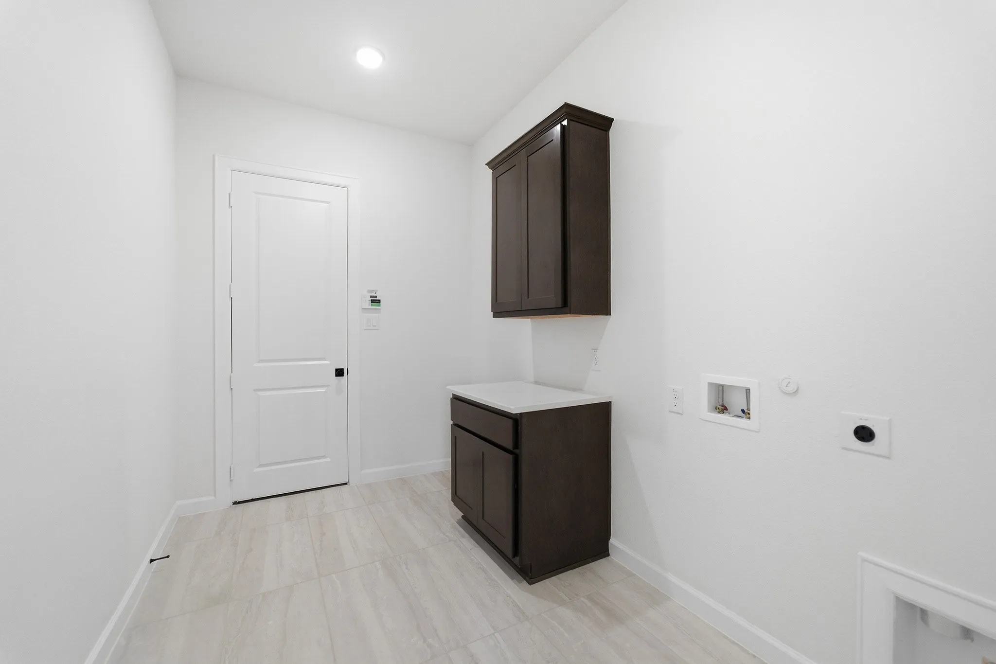 Utility room featuring dark wood-finish cabinetry with a light-toned countertop, recessed lighting, and tile flooring