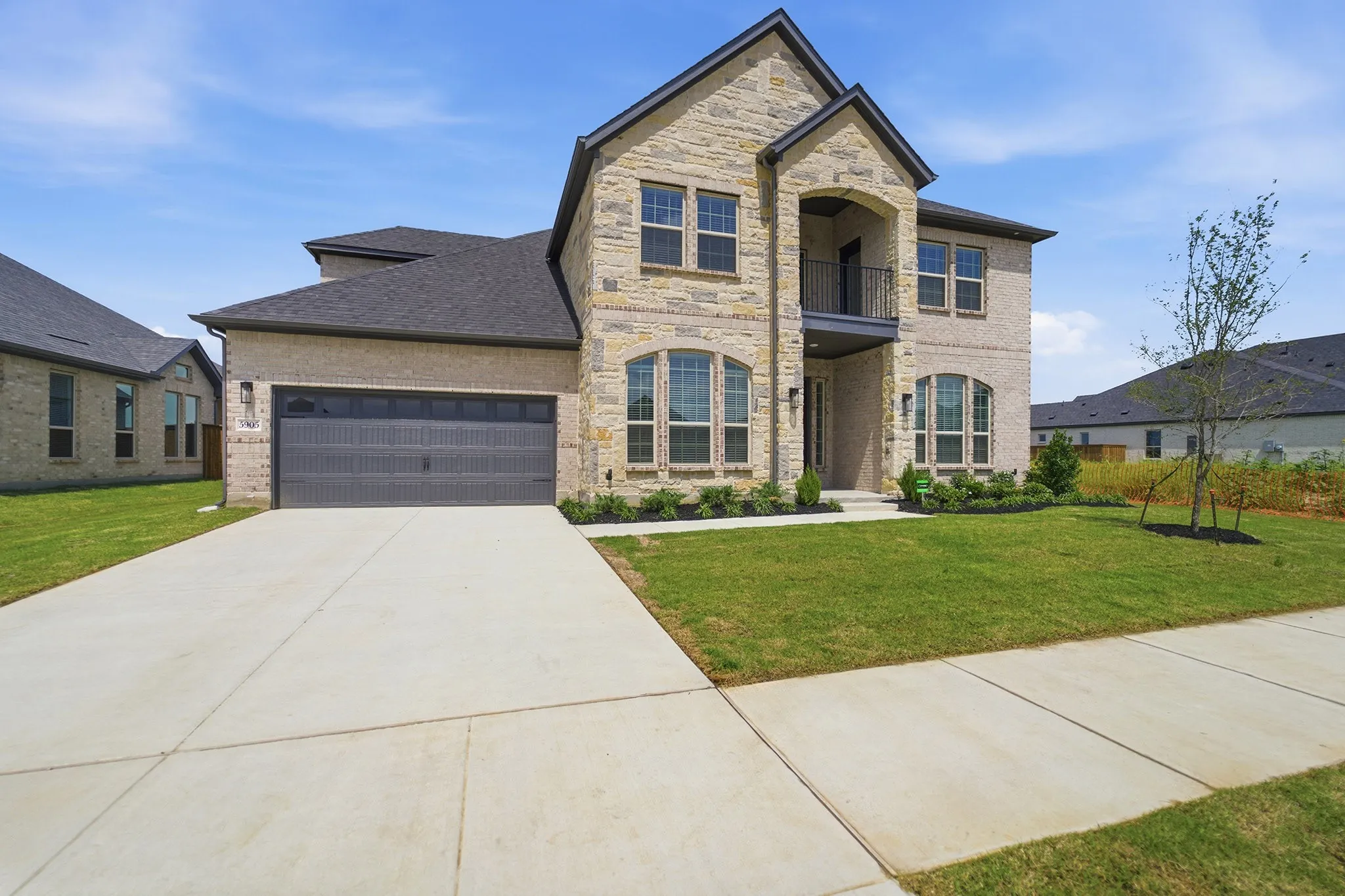 Two-story residence featuring light-toned brick and dark trim