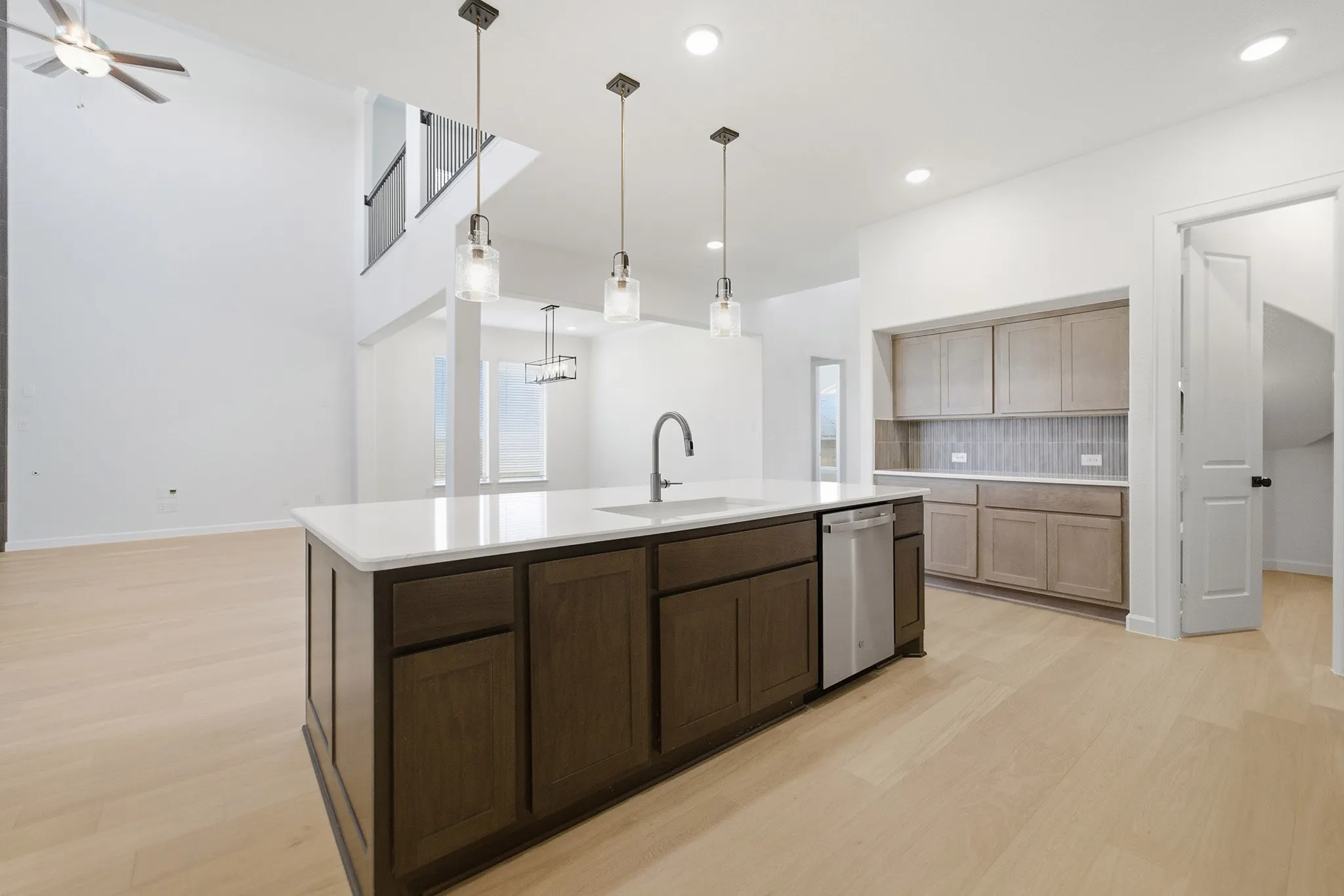 Modern kitchen island featuring dark wood cabinetry, a white countertop, and an integrated stainless steel dishwasher