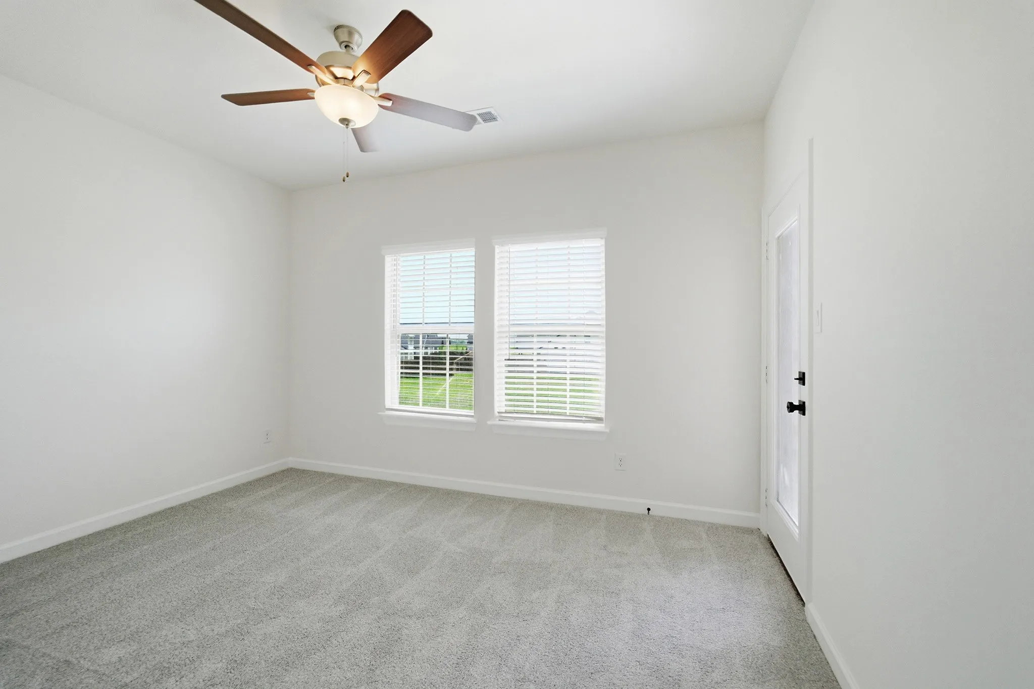 Room featuring light gray carpet flooring, white walls, and a ceiling fan with light fixture