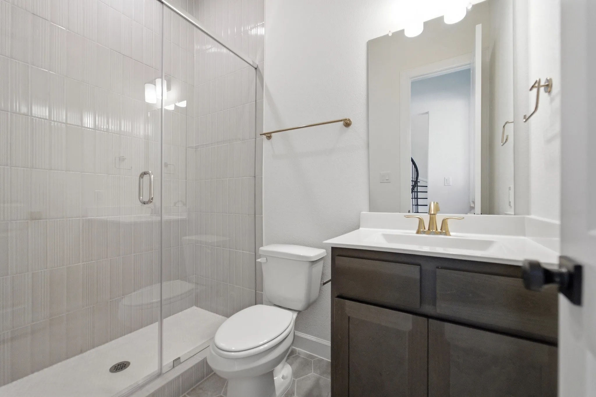 Shower with a clear glass enclosure and vertically stacked white tile, featuring a white shower pan