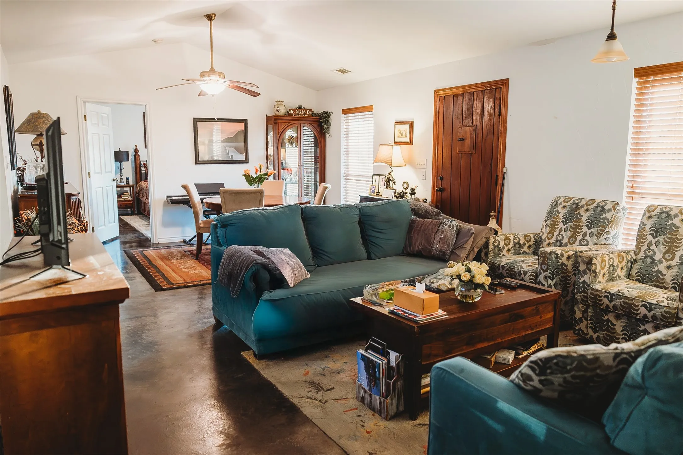 Living room with lofted ceiling, finished concrete flooring, and ceiling fan