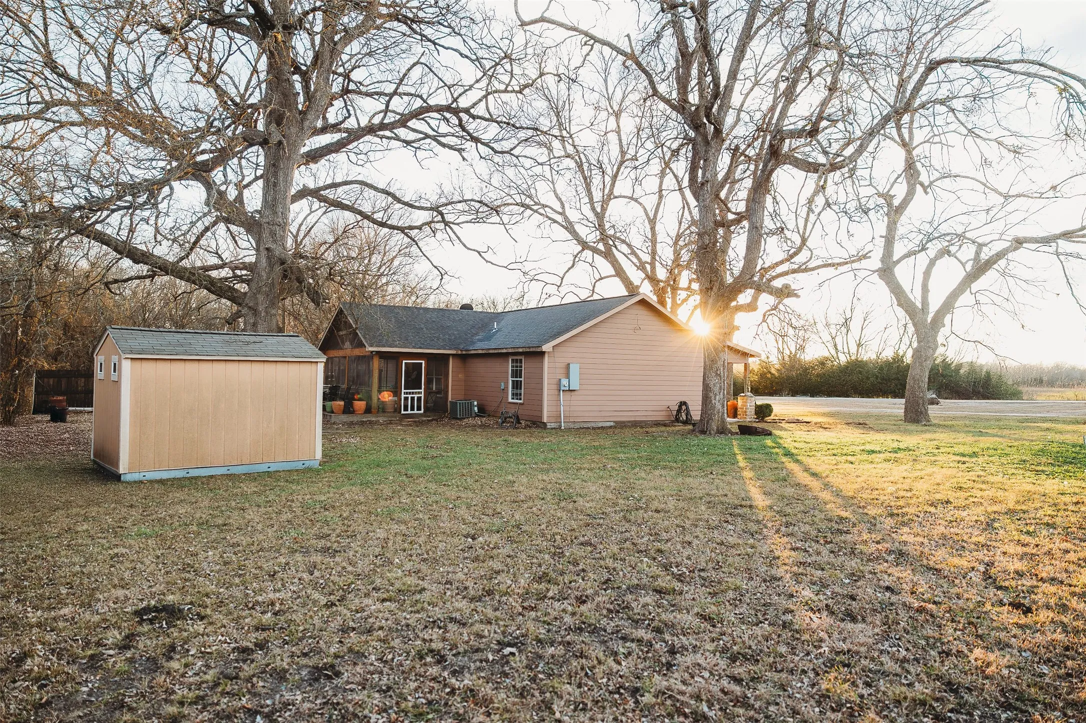Rear view of property with a storage unit and a lawn
