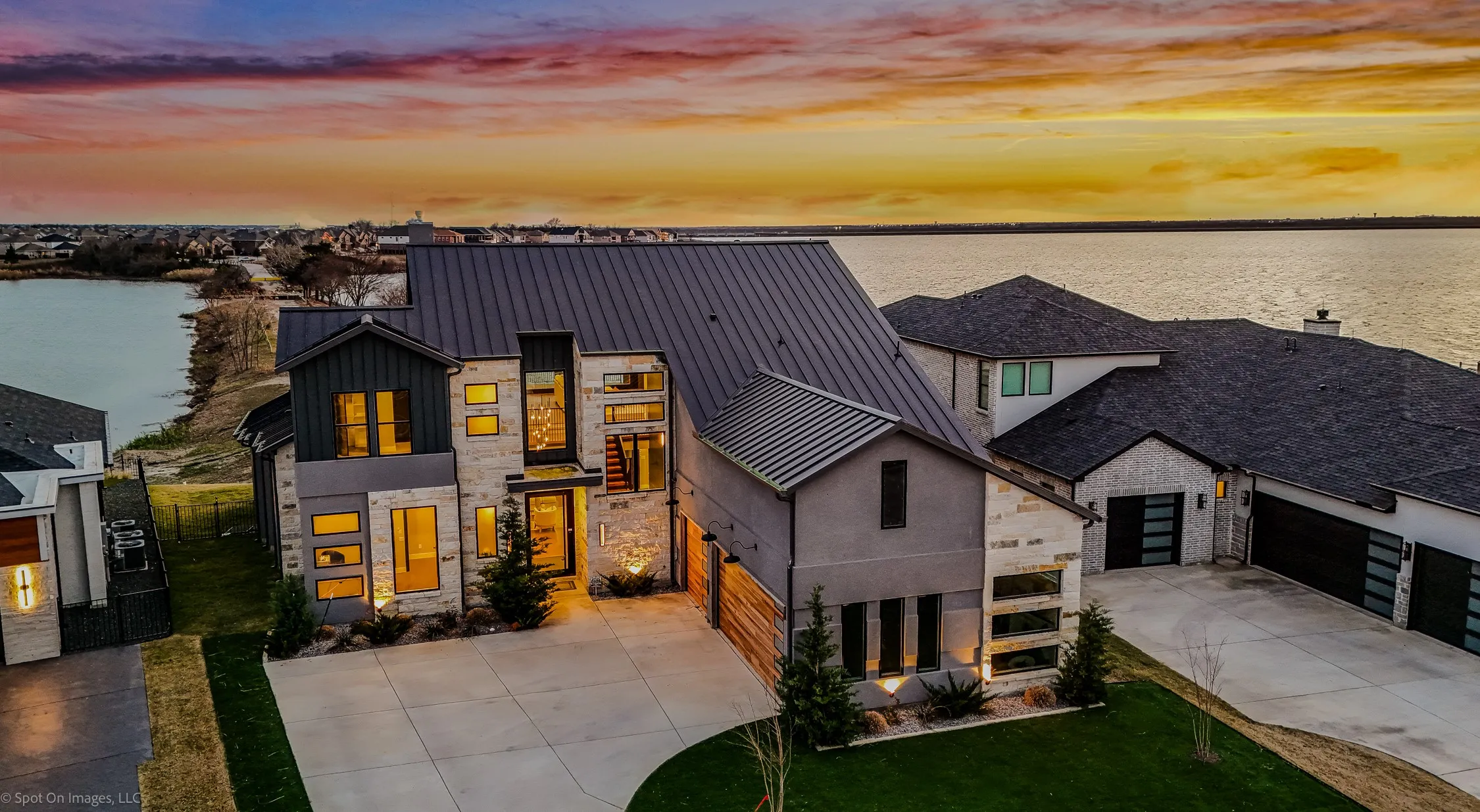 View of front of property featuring stone siding, a lawn, a standing seam roof, and driveway