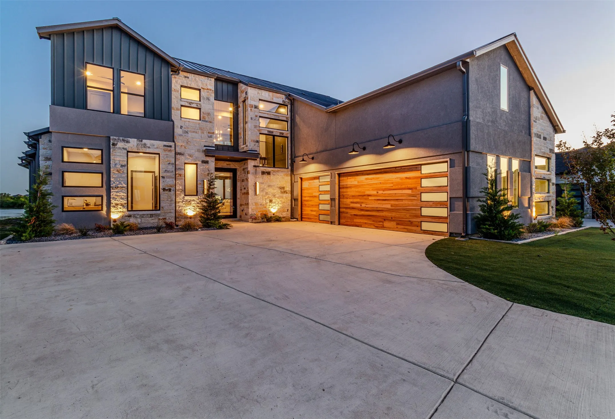 Contemporary house with concrete driveway, stone siding, a garage, and board and batten siding