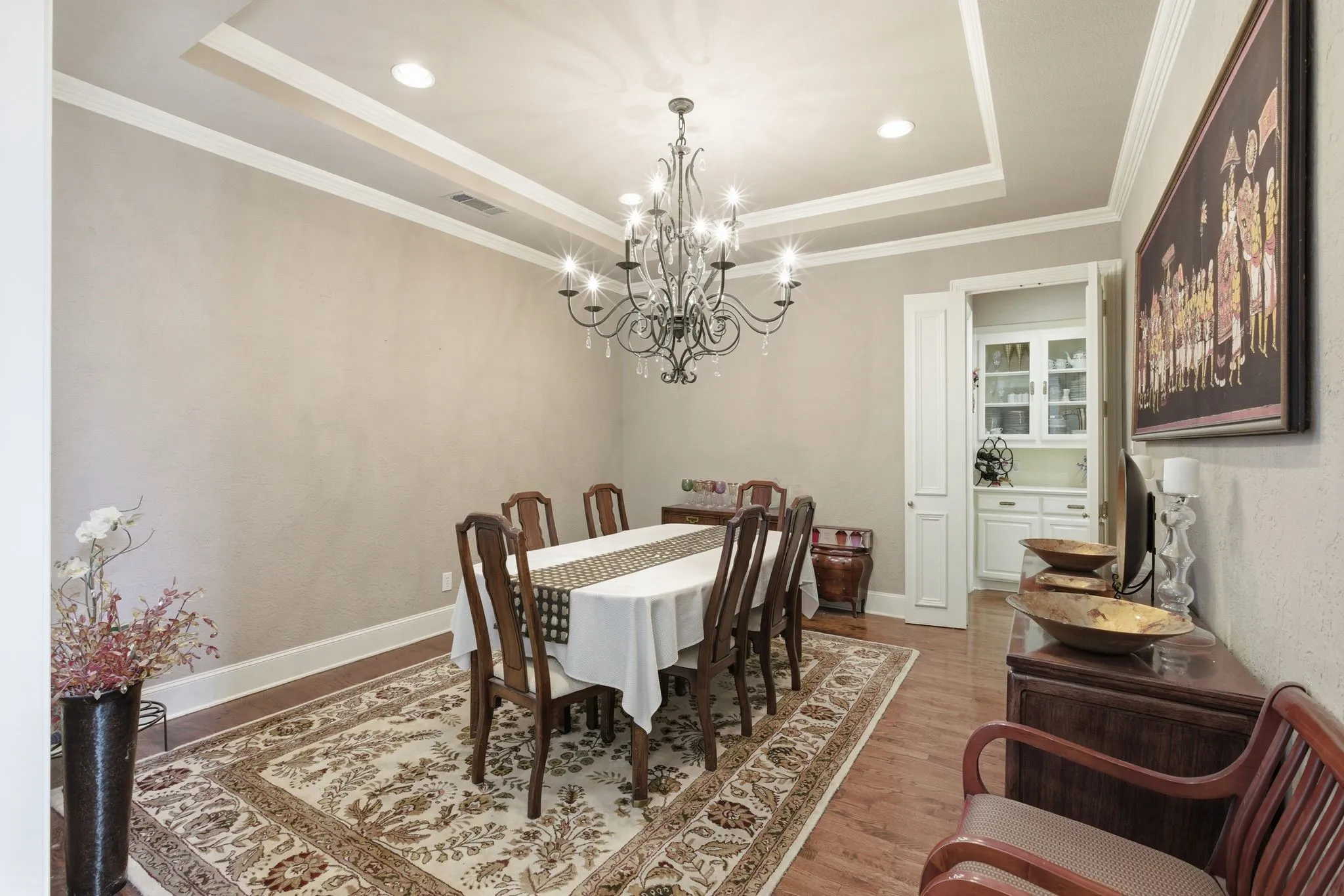 Dining space featuring wood finished floors, suspended lighting, a tray ceiling, and ornamental molding