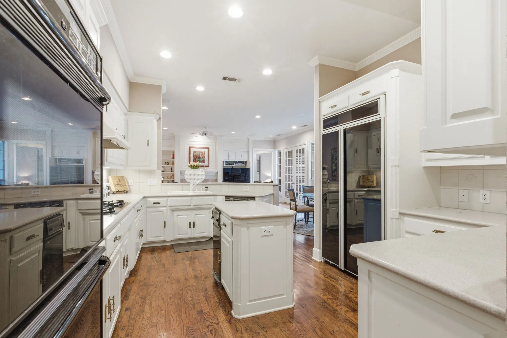 Kitchen with crown molding, an Island, tasteful backsplash, built in refrigerator, and dark wood-style flooring