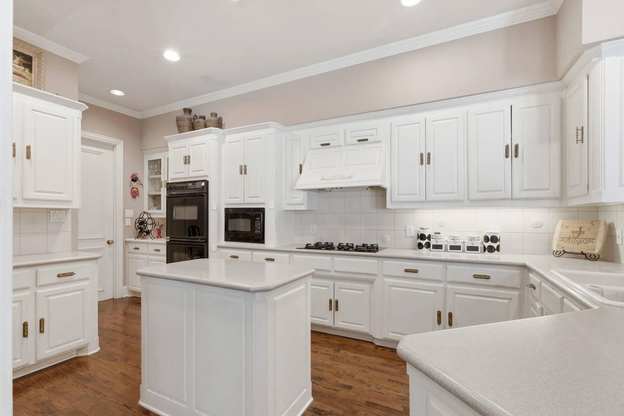 Kitchen featuring ornamental molding, dark wood-style flooring, light countertops, white cabinets, and recessed lighting