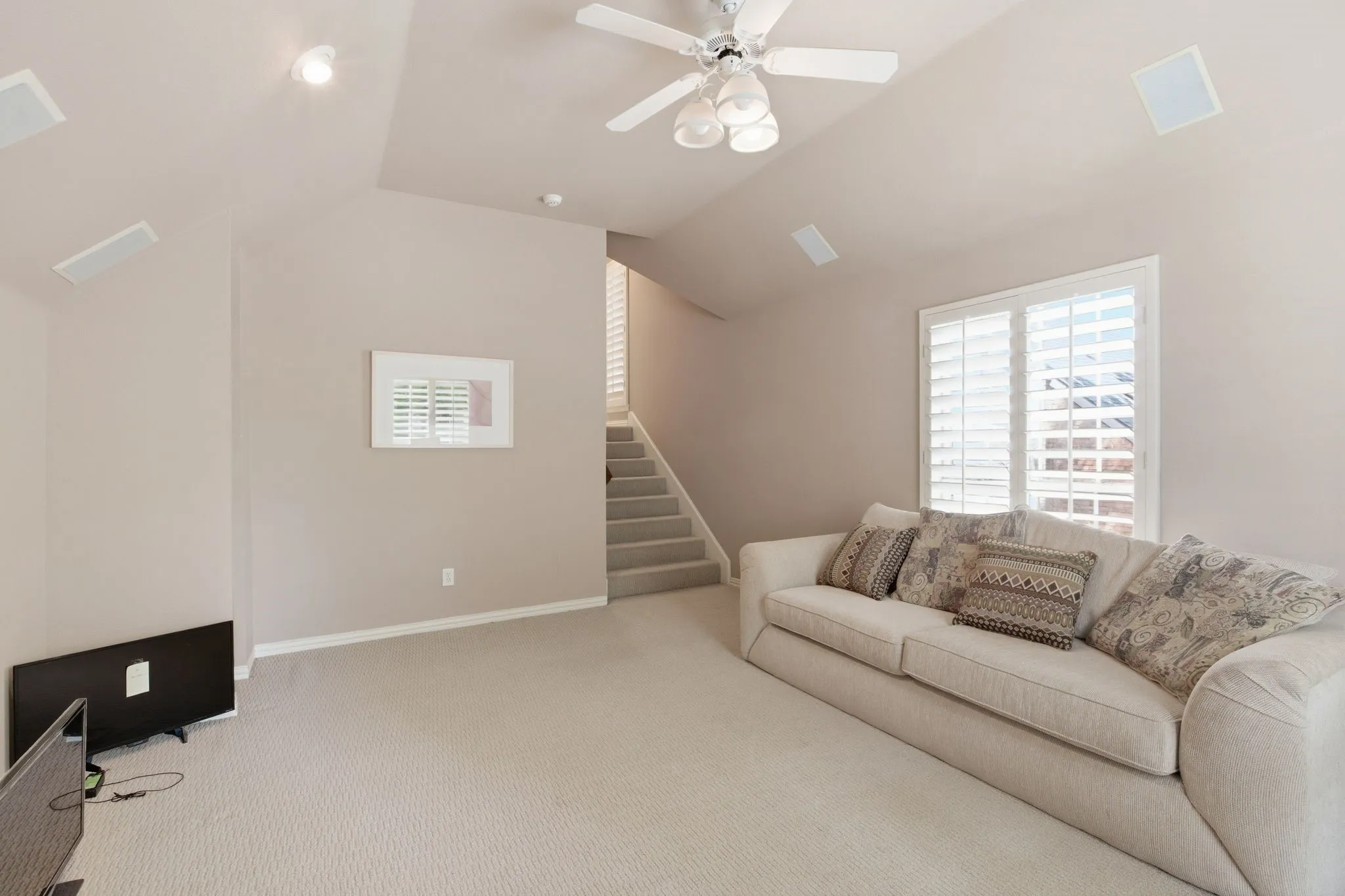 Living area with ceiling fan, light carpet, and vaulted ceiling