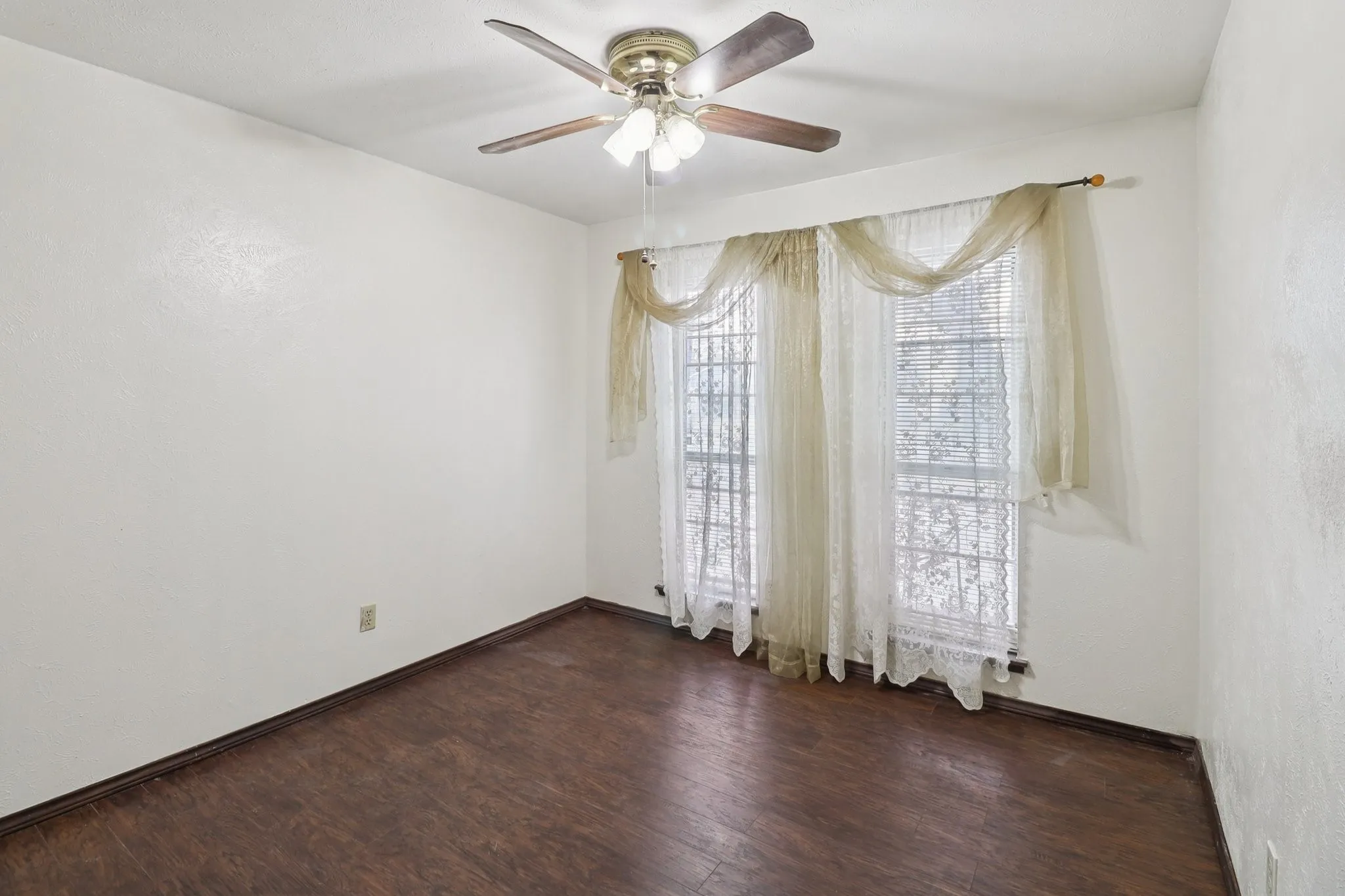 One of the bedrooms with a laminate wood floor, ceiling fan, and closet.