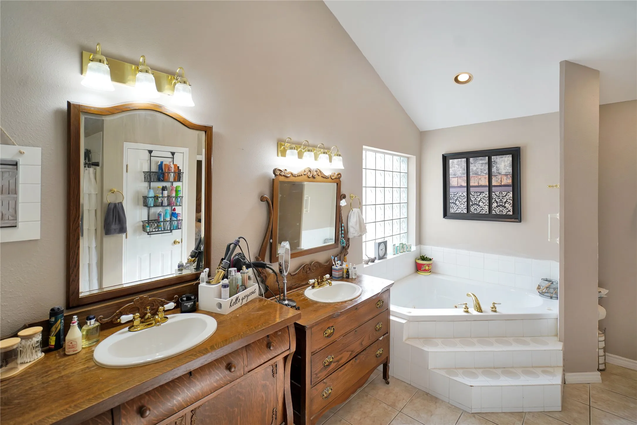 Full bathroom featuring lofted ceiling, two vanities, a bath, light tile patterned flooring, and recessed lighting