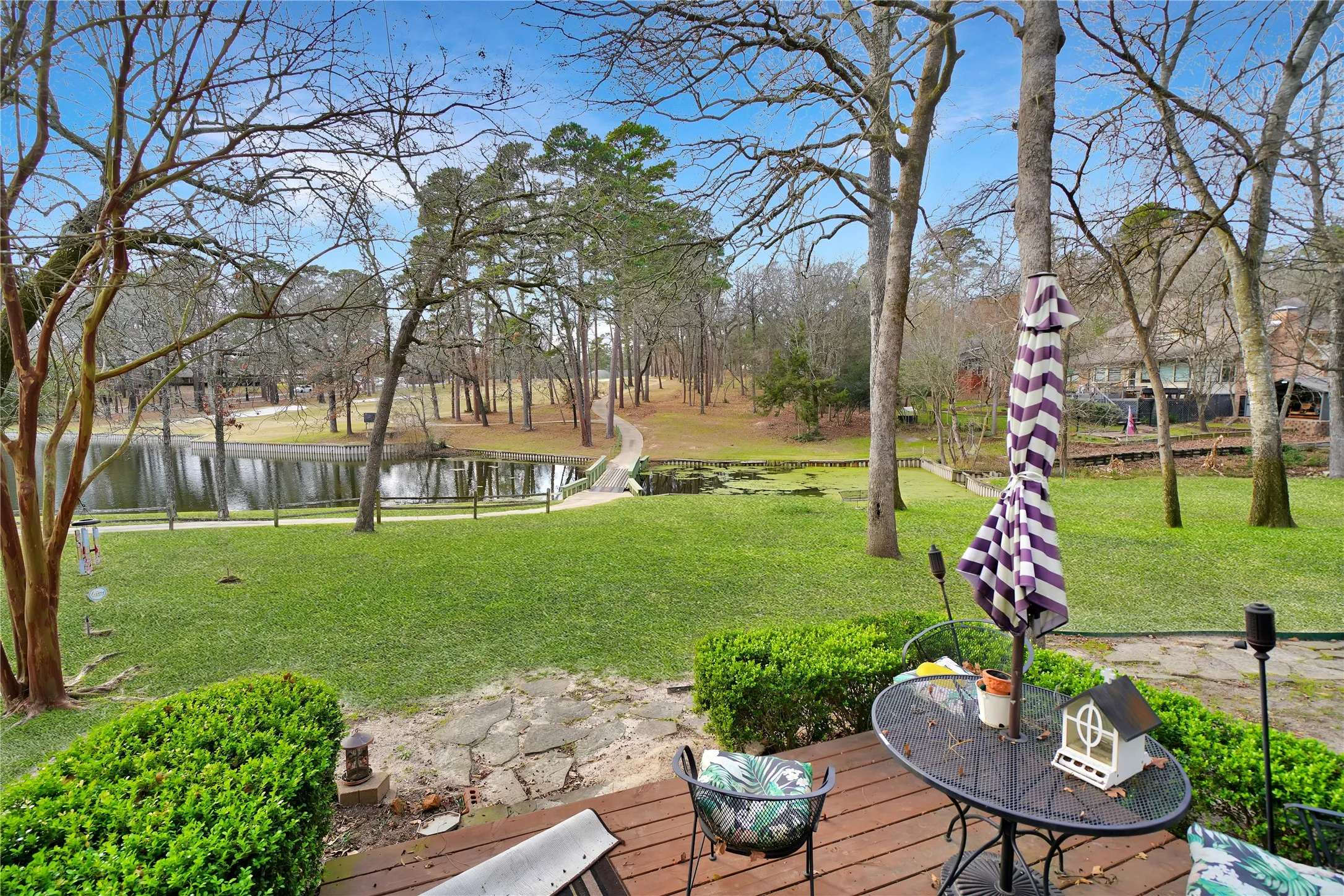 View of green lawn featuring a deck with water view