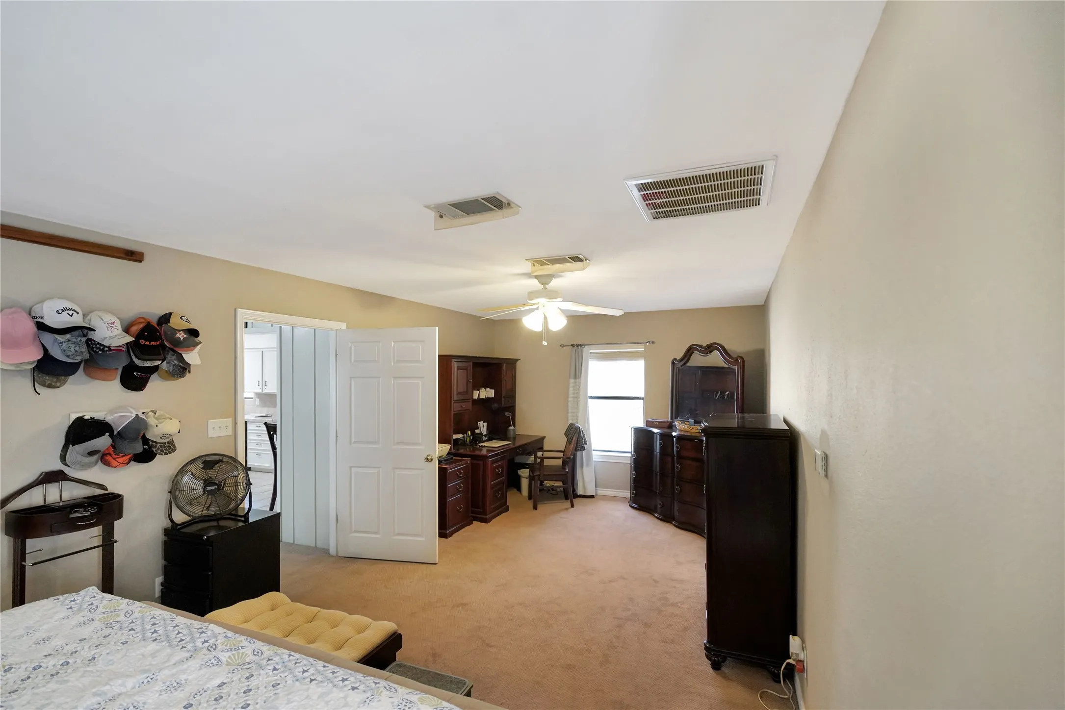 Bedroom with light colored carpet, ceiling fan, and a desk