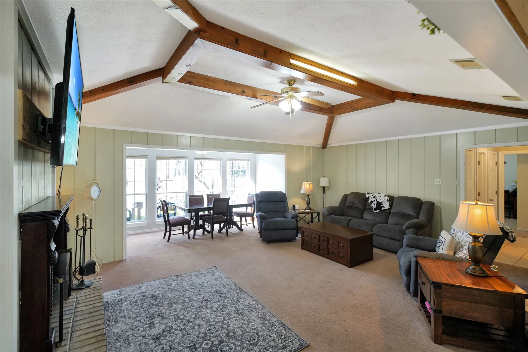 Living area with light carpet, ceiling fan, and a decorative wall