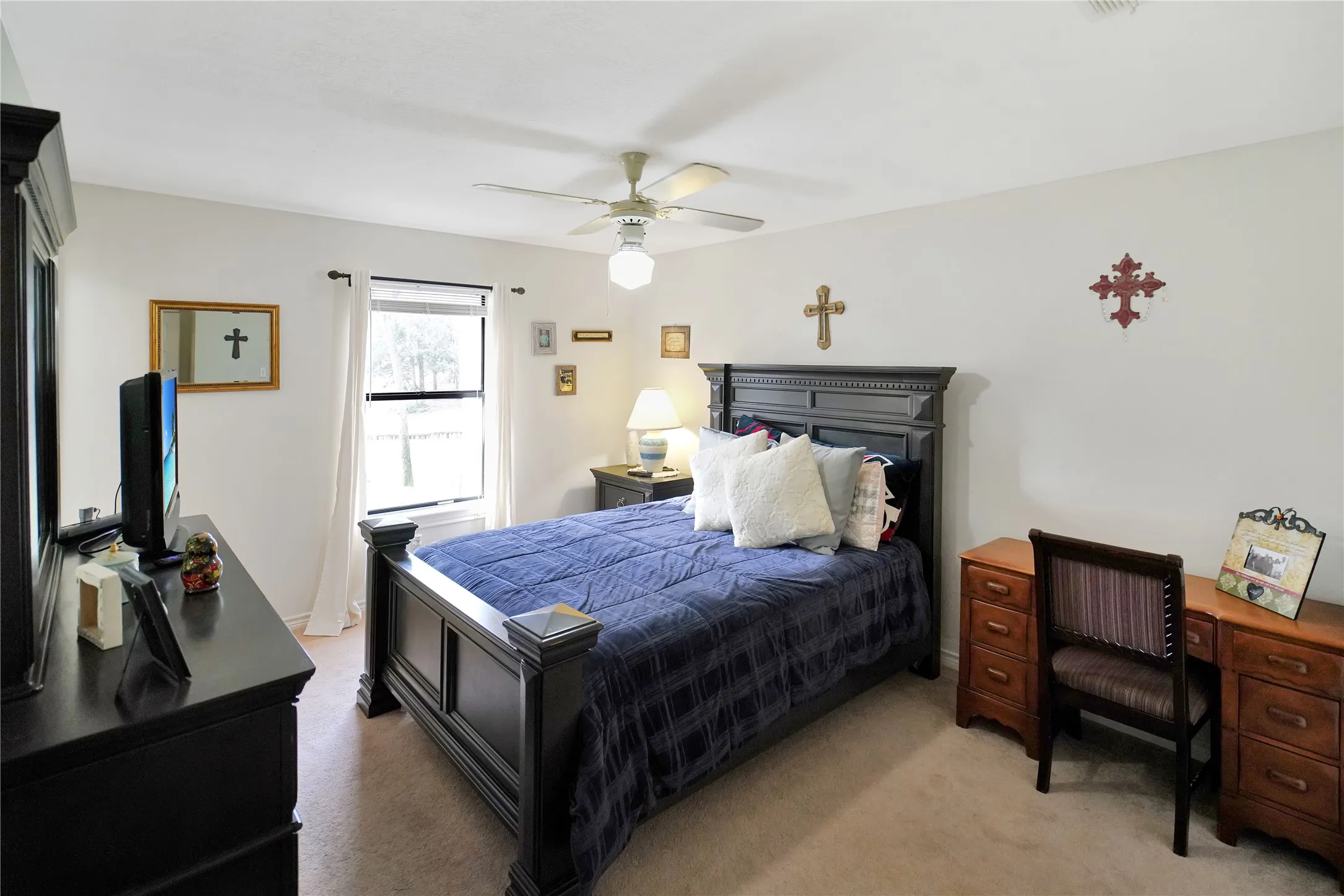 Bedroom with light colored carpet, a ceiling fan, and a desk