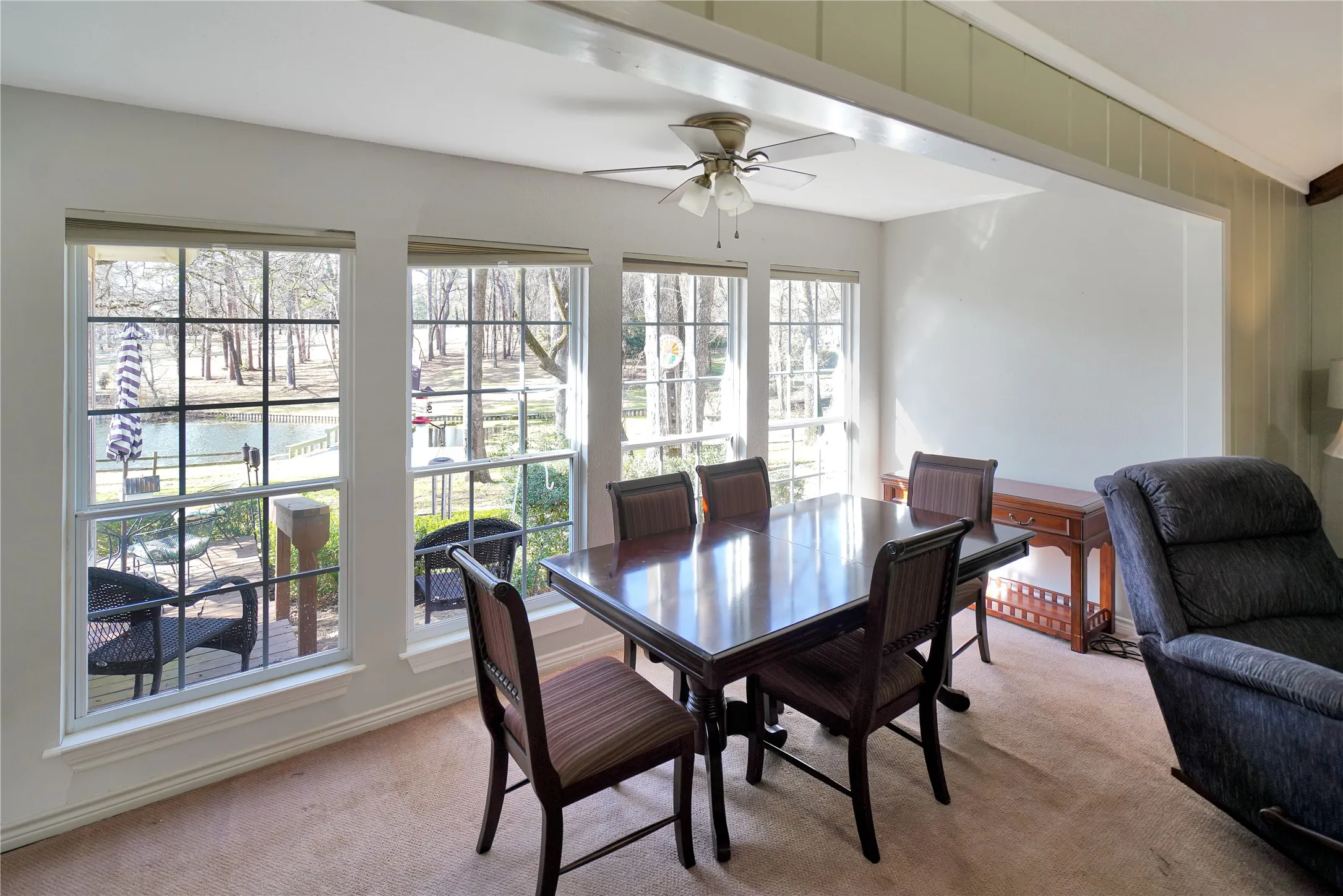 Carpeted dining space with ceiling fan and crown molding