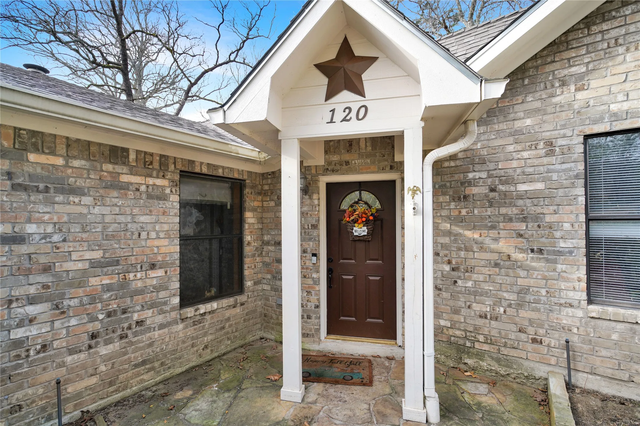 View of exterior entry featuring roof with shingles and brick siding