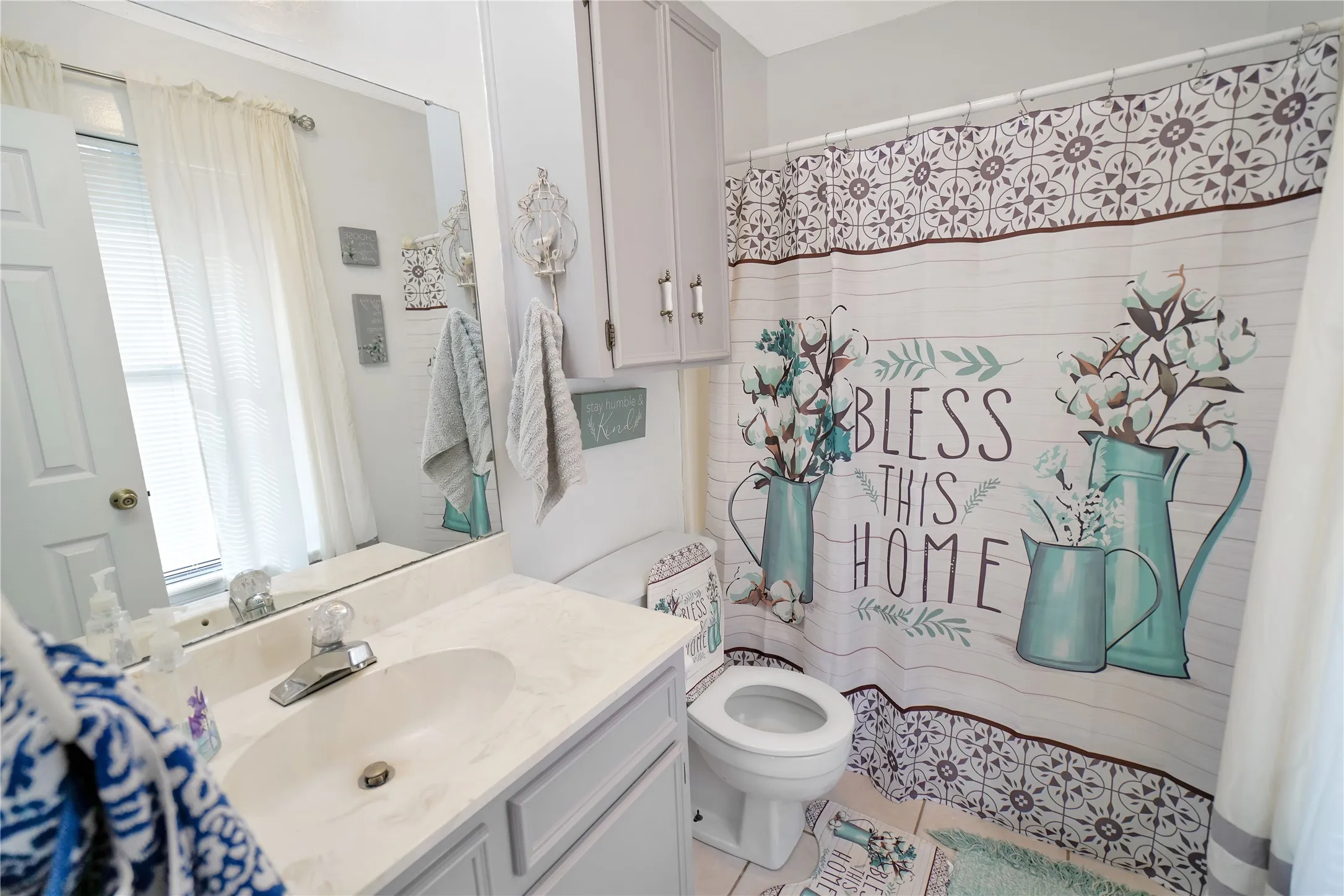 Full bathroom with vanity, light tile patterned floors, and a shower with curtain