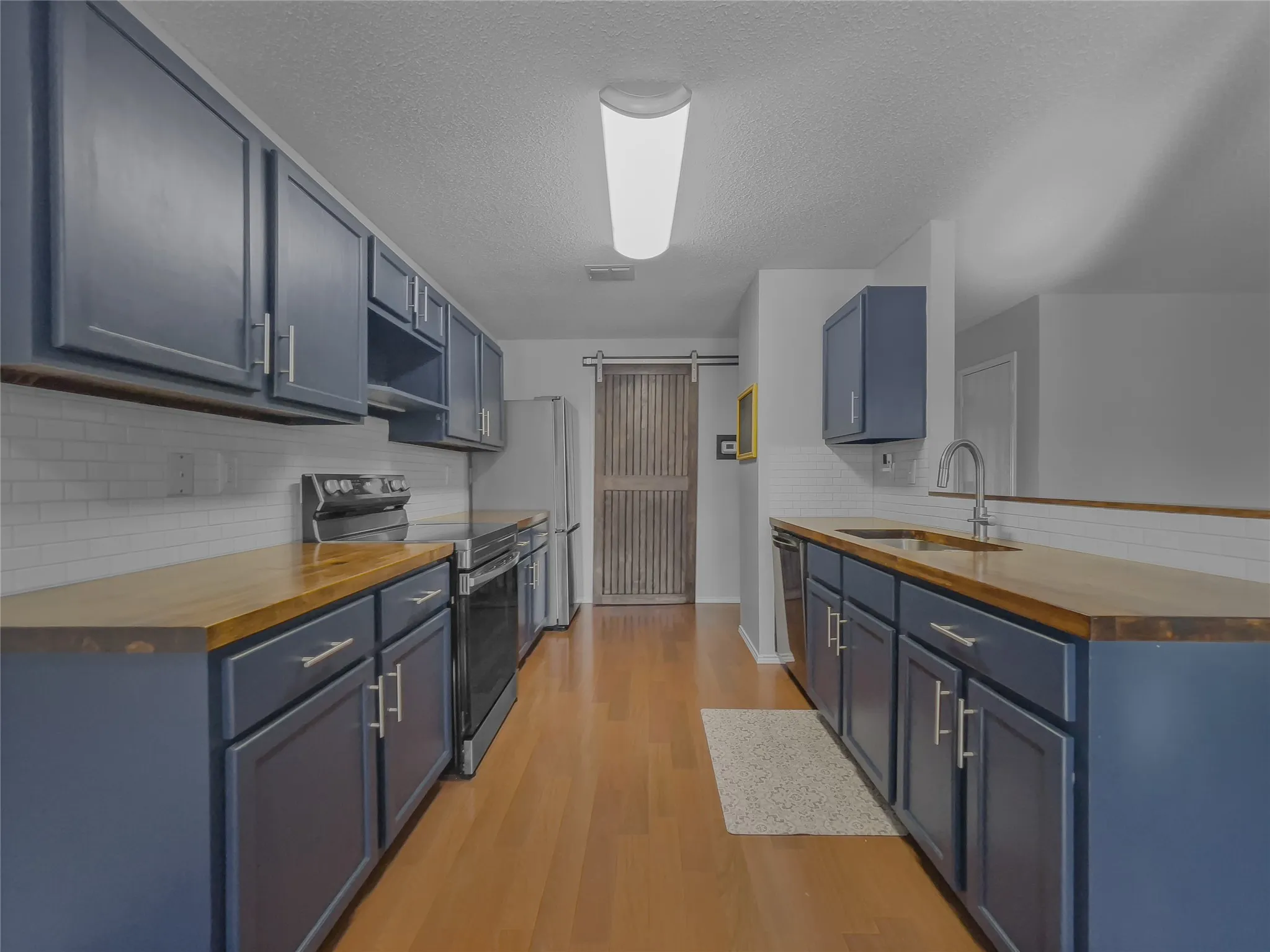 Kitchen view of butcher block counters and custom-painted cabinets