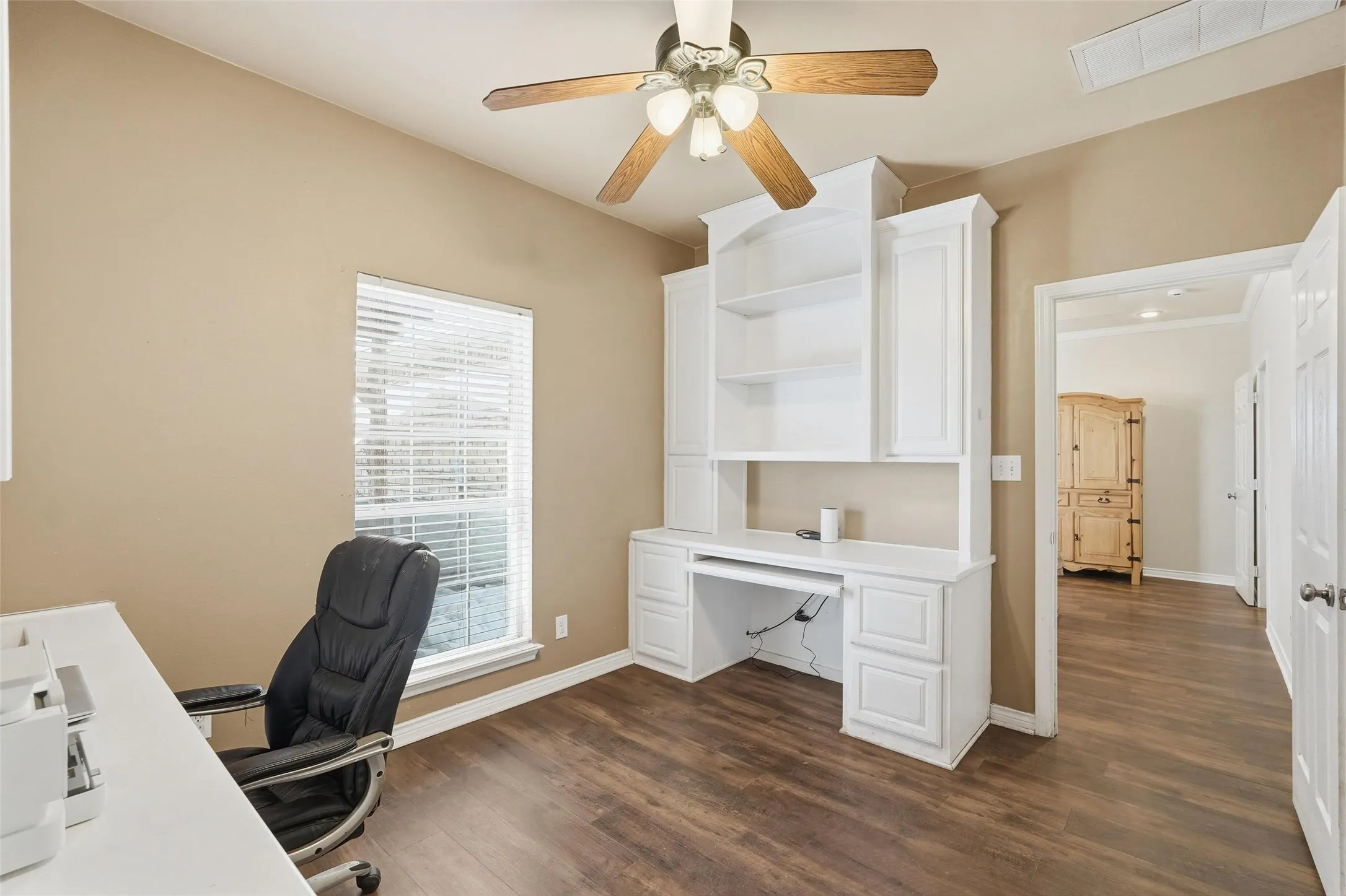 Two built in desks and ceiling fan in office.