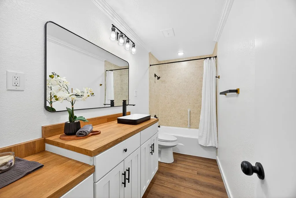 Bathroom with vanity, shower / tub combo, crown molding, dark wood-style floors, and a textured wall