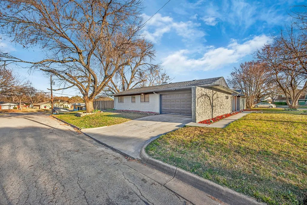 View of front of property featuring driveway, a garage, brick siding, and a residential view