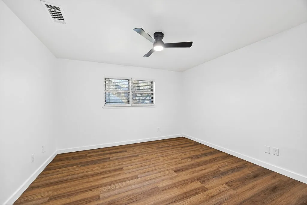 Spare room with dark wood-type flooring and a ceiling fan