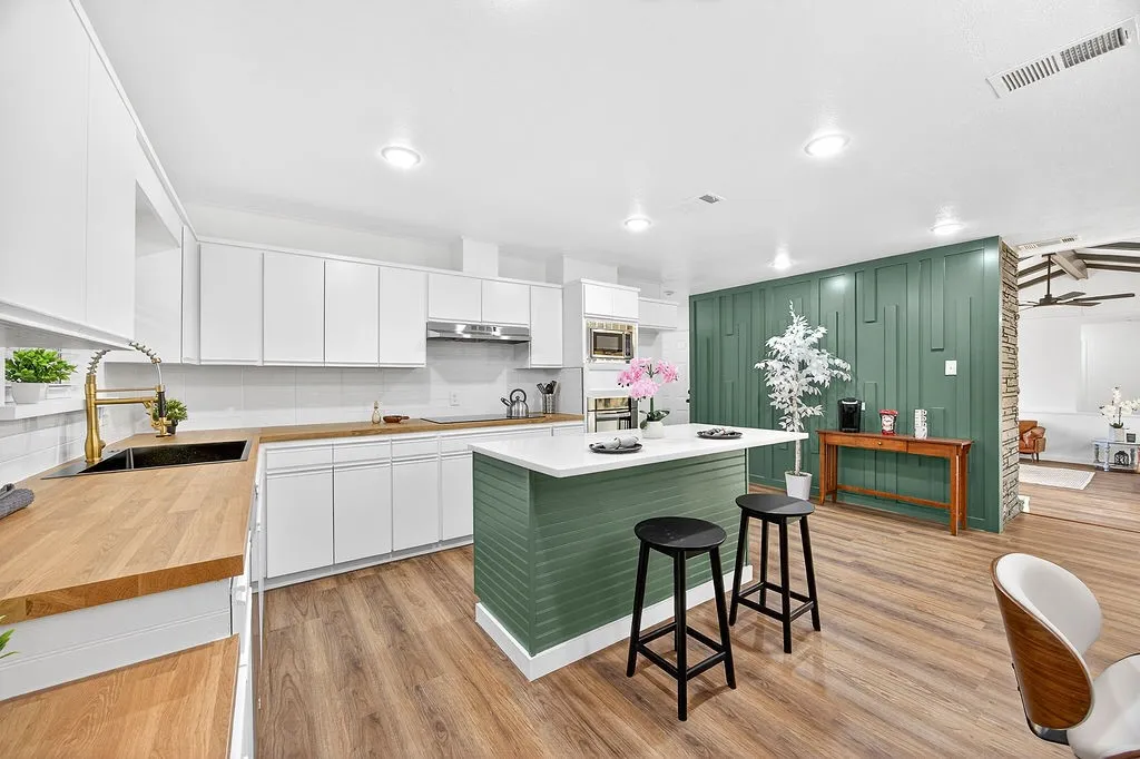 Kitchen with white cabinetry, green cabinetry, a kitchen bar, a center island, and light wood-style flooring