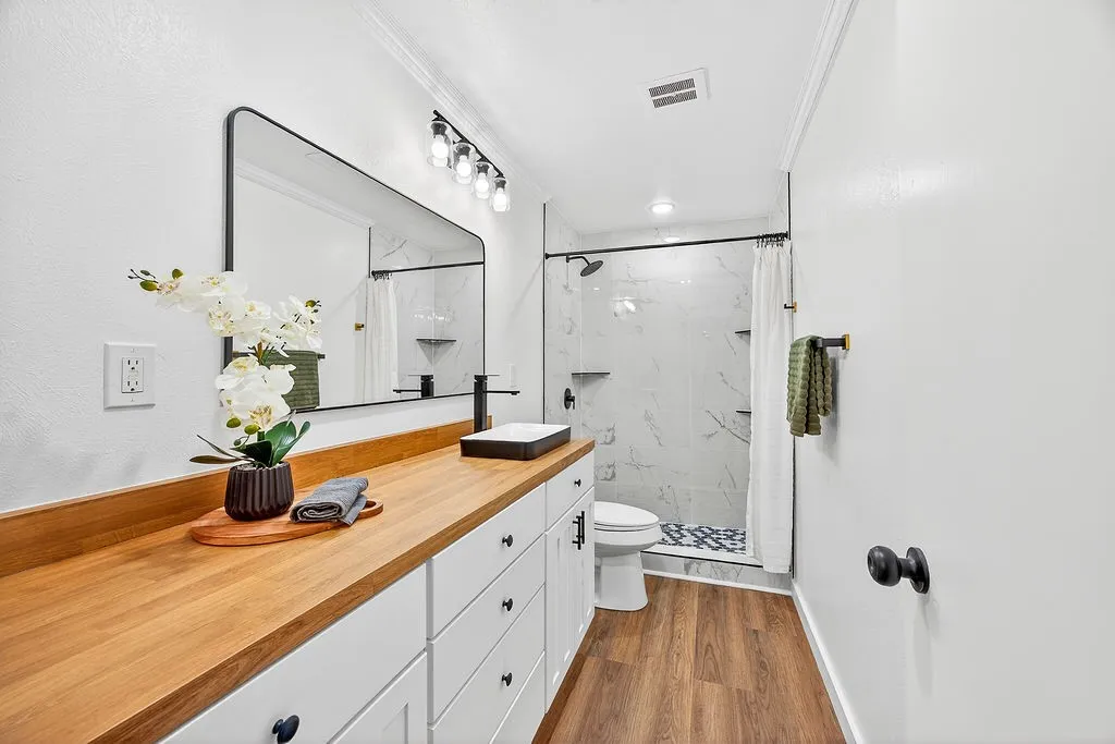 Bathroom featuring a marble finish shower, vanity, dark wood-type flooring, and crown molding