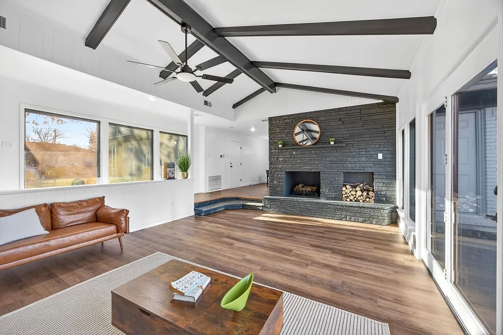 Living area with a fireplace, wood finished floors, and a ceiling fan