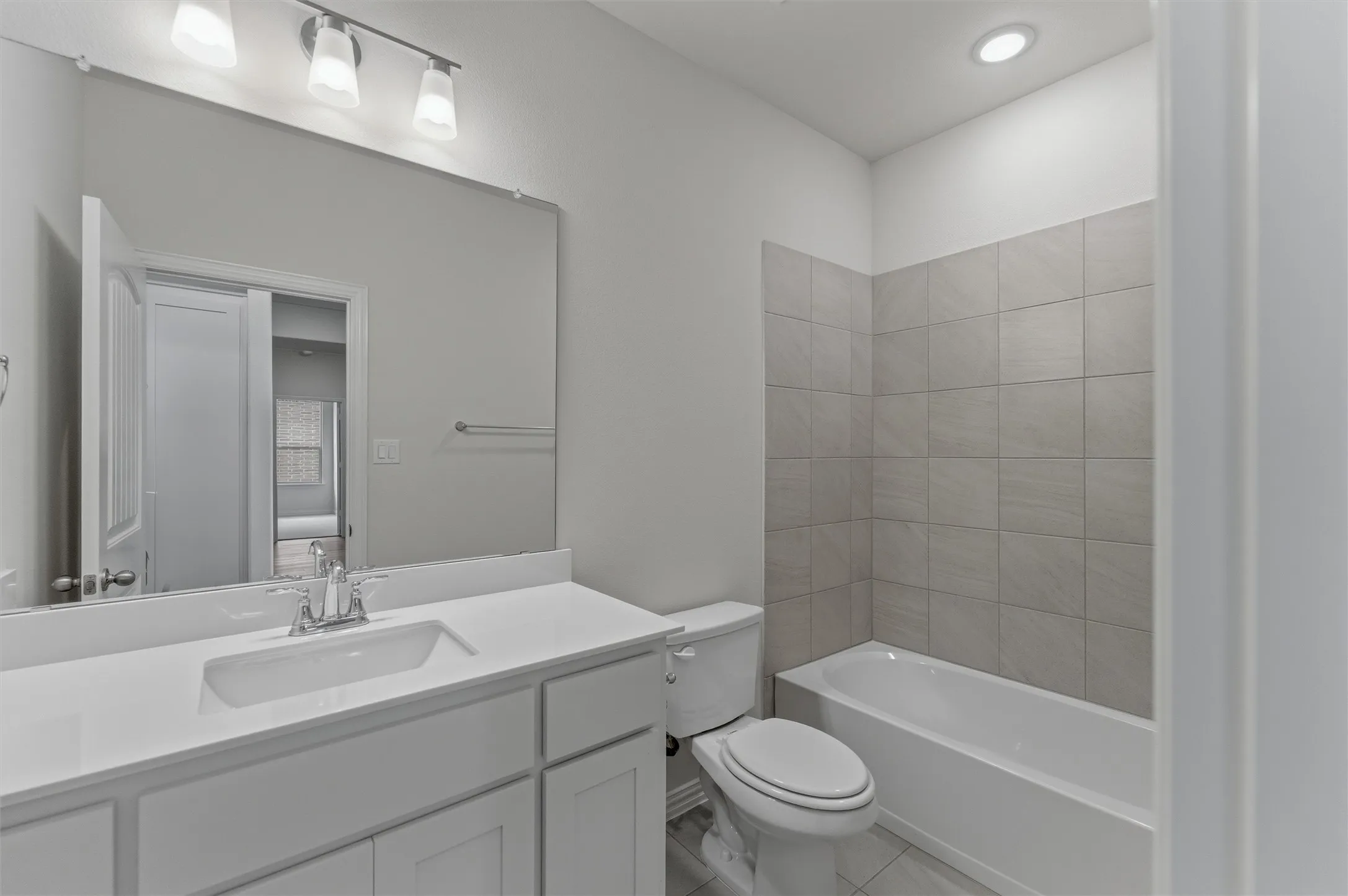 Full bathroom featuring a white vanity with an integrated sink, polished chrome faucet, and a large mirror