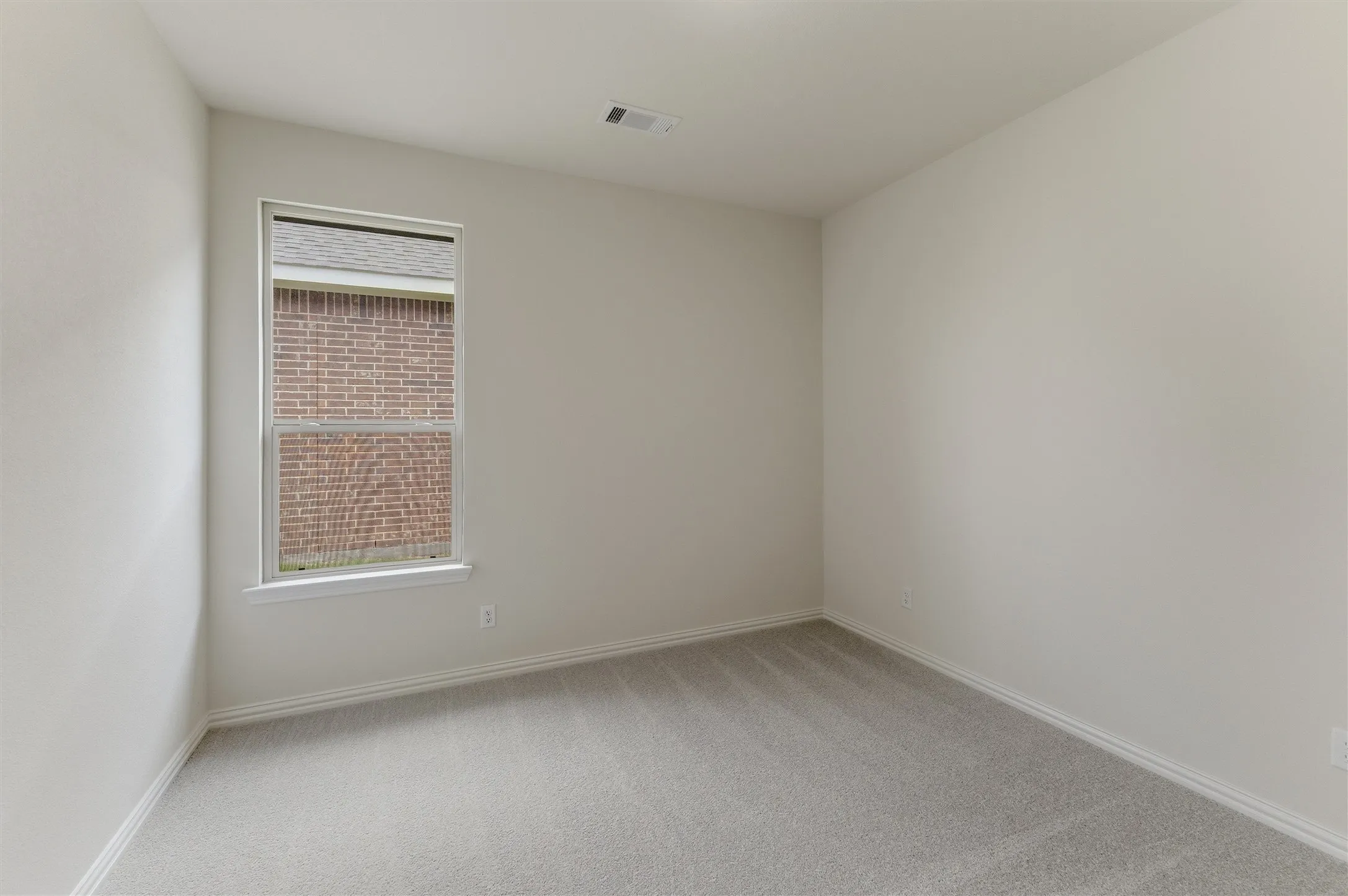 Bright interior room featuring a single window, light gray carpeting, and neutral-toned wall paint