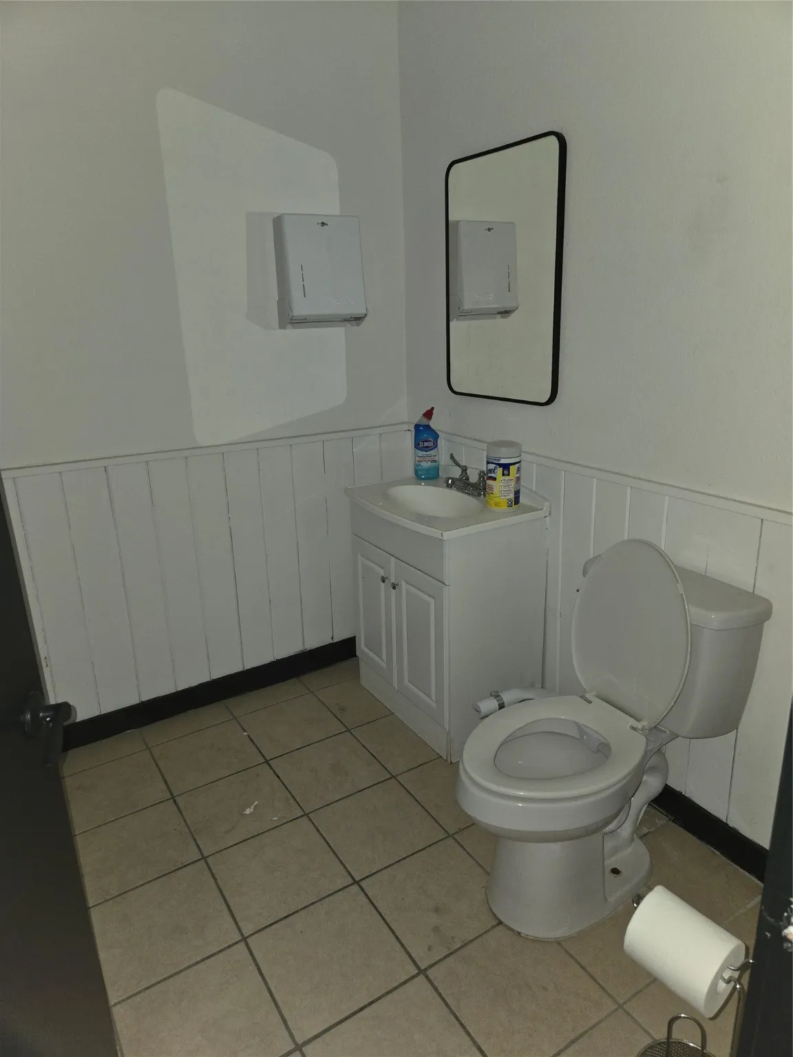 Half bathroom with wainscoting, vanity, and light tile patterned floors