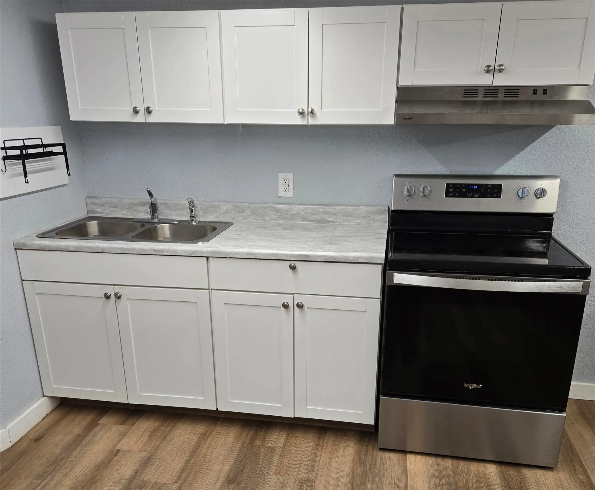 Kitchen featuring electric stove, light countertops, white cabinetry, dark wood-style floors, and a textured wall