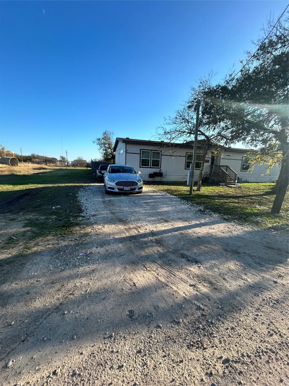 View of front facade with dirt driveway and a front lawn