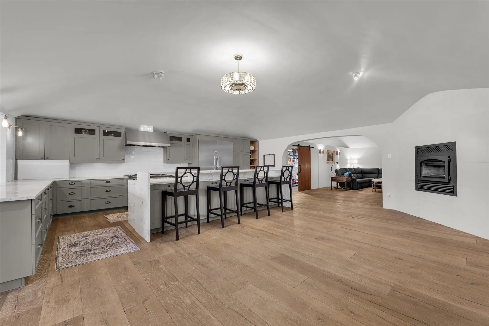 Kitchen with gray cabinetry, a kitchen bar, open floor plan, fireplace and light wood-style floors