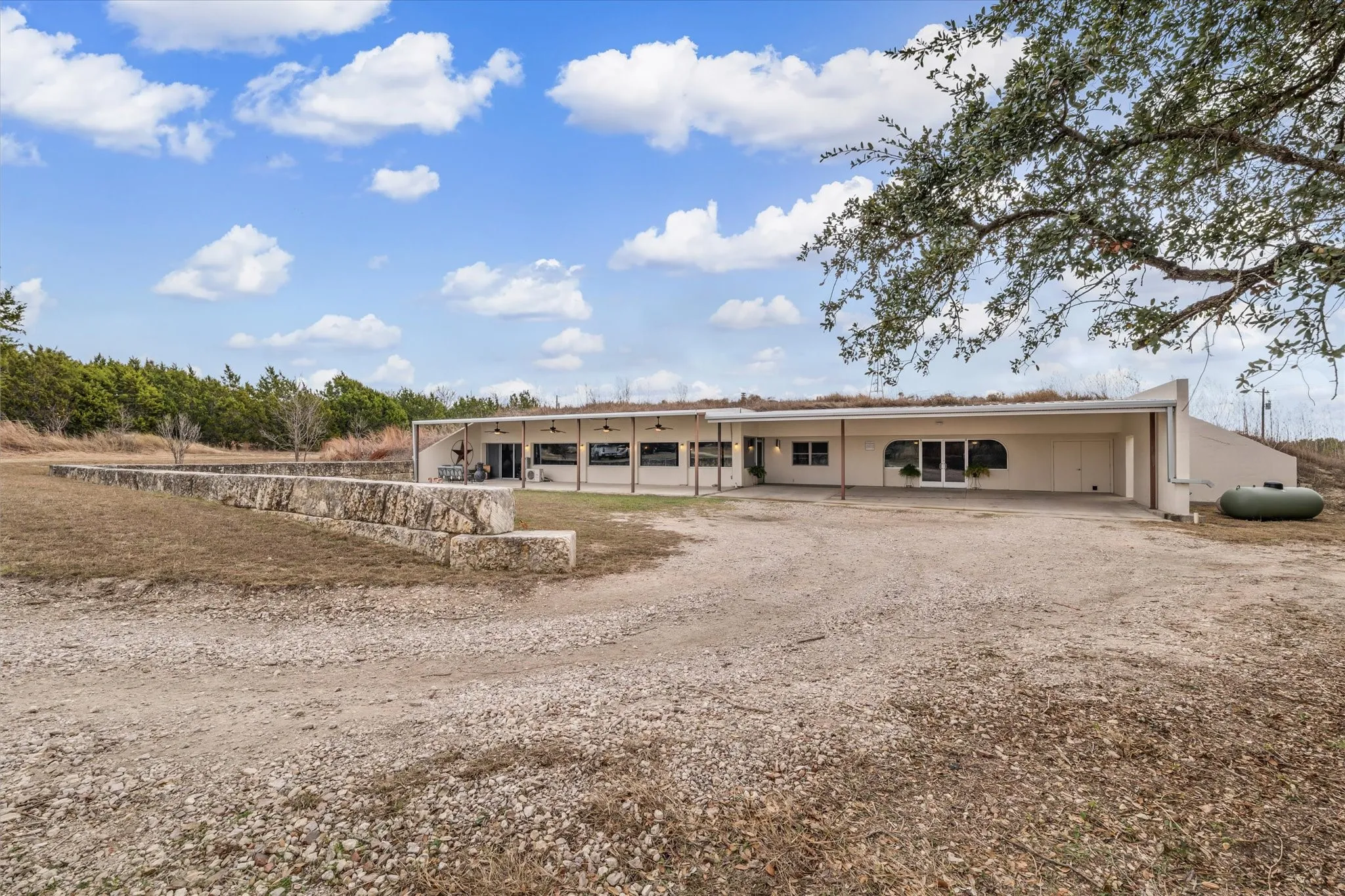 Front view of property featuring a patio area, ceiling fan, and a carport