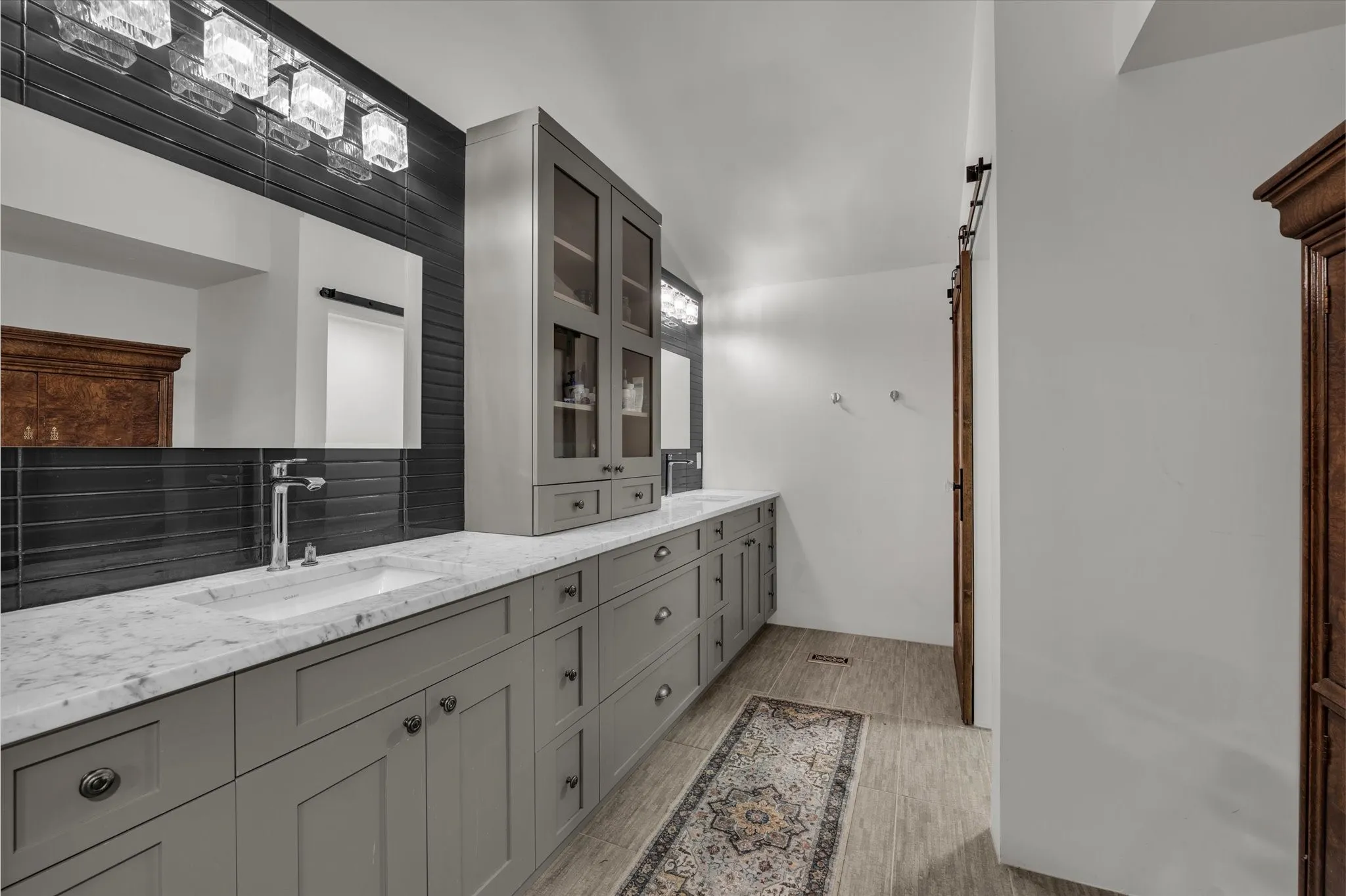 Full bathroom with double vanity, wood finish floors, and decorative backsplash