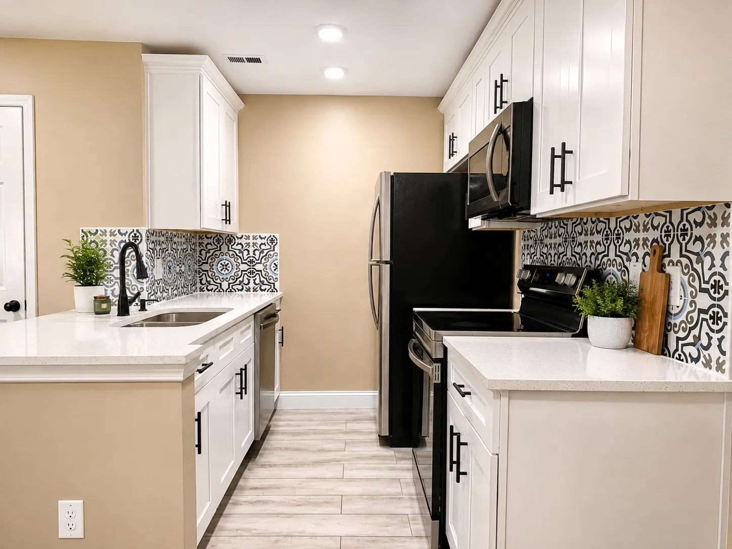 White shaker cabinetry with matte black hardware, mosaic tile backsplash, solid surface countertops, stainless steel sink with matte black faucet, and wood-finish flooring