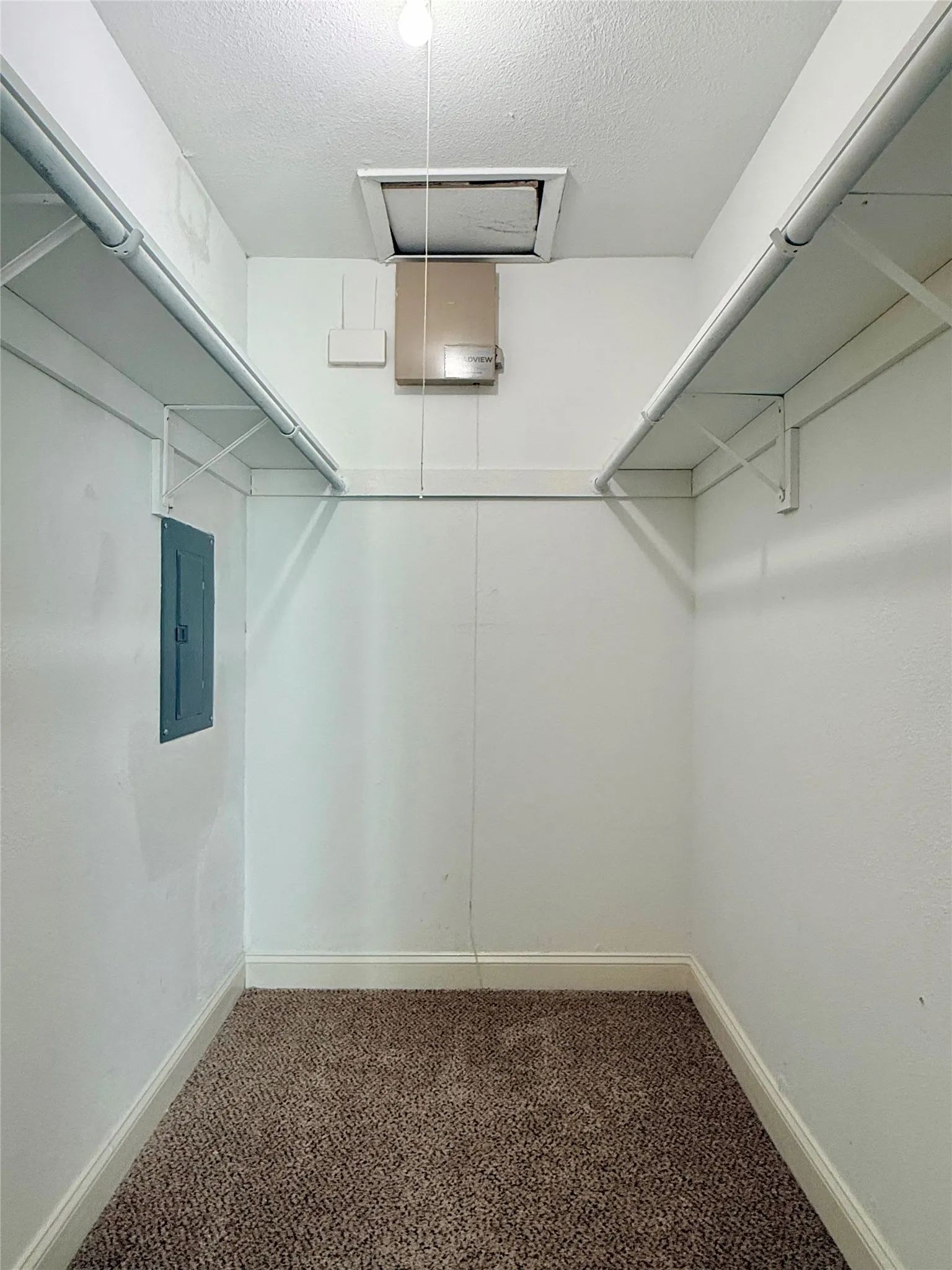 Walk in closet featuring carpet, electric panel, and attic access