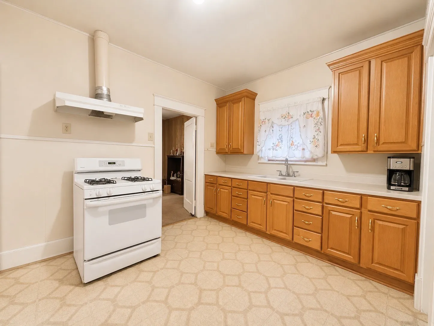Kitchen featuring wood-finish cabinetry, light countertops, and a white gas range with coordinating range hood