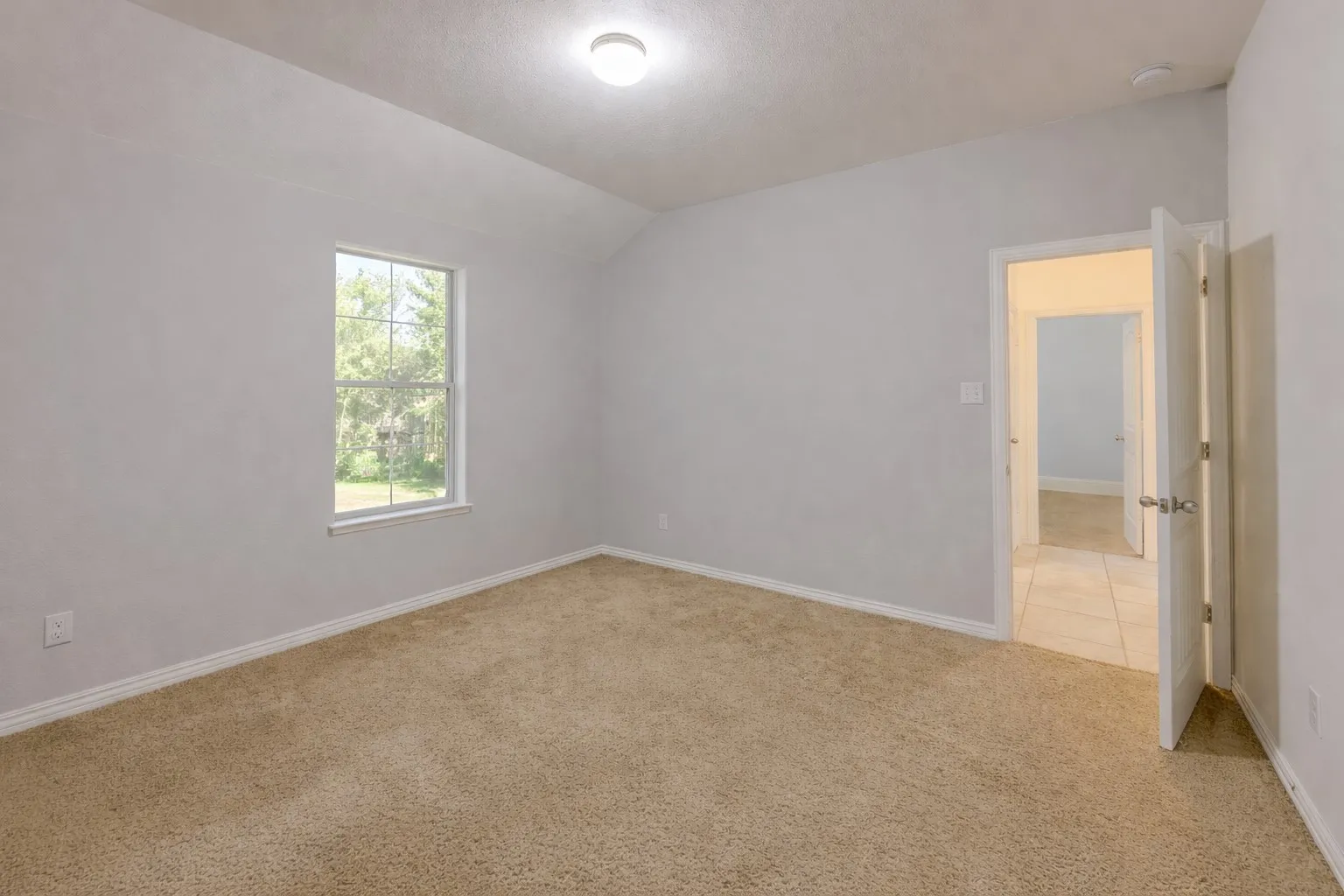Empty room with light carpet, lofted ceiling, and a textured ceiling