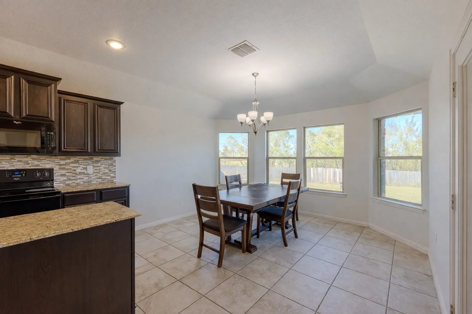 Dining area featuring light tile patterned floors, a chandelier, and lofted ceiling