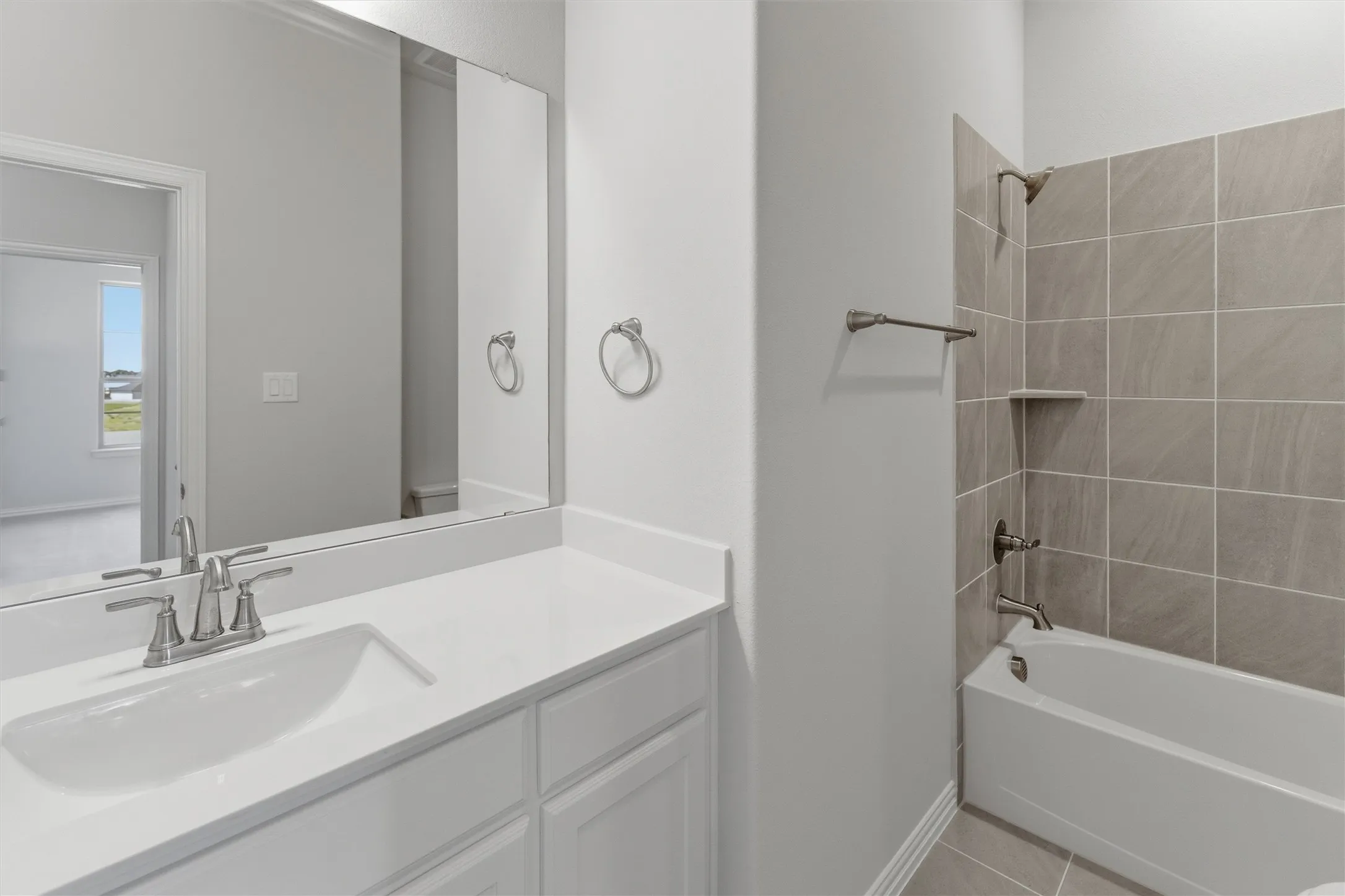 Bathroom featuring a vanity with a white countertop and an integrated sink, brushed nickel faucet, and a large wall-mounted mirror