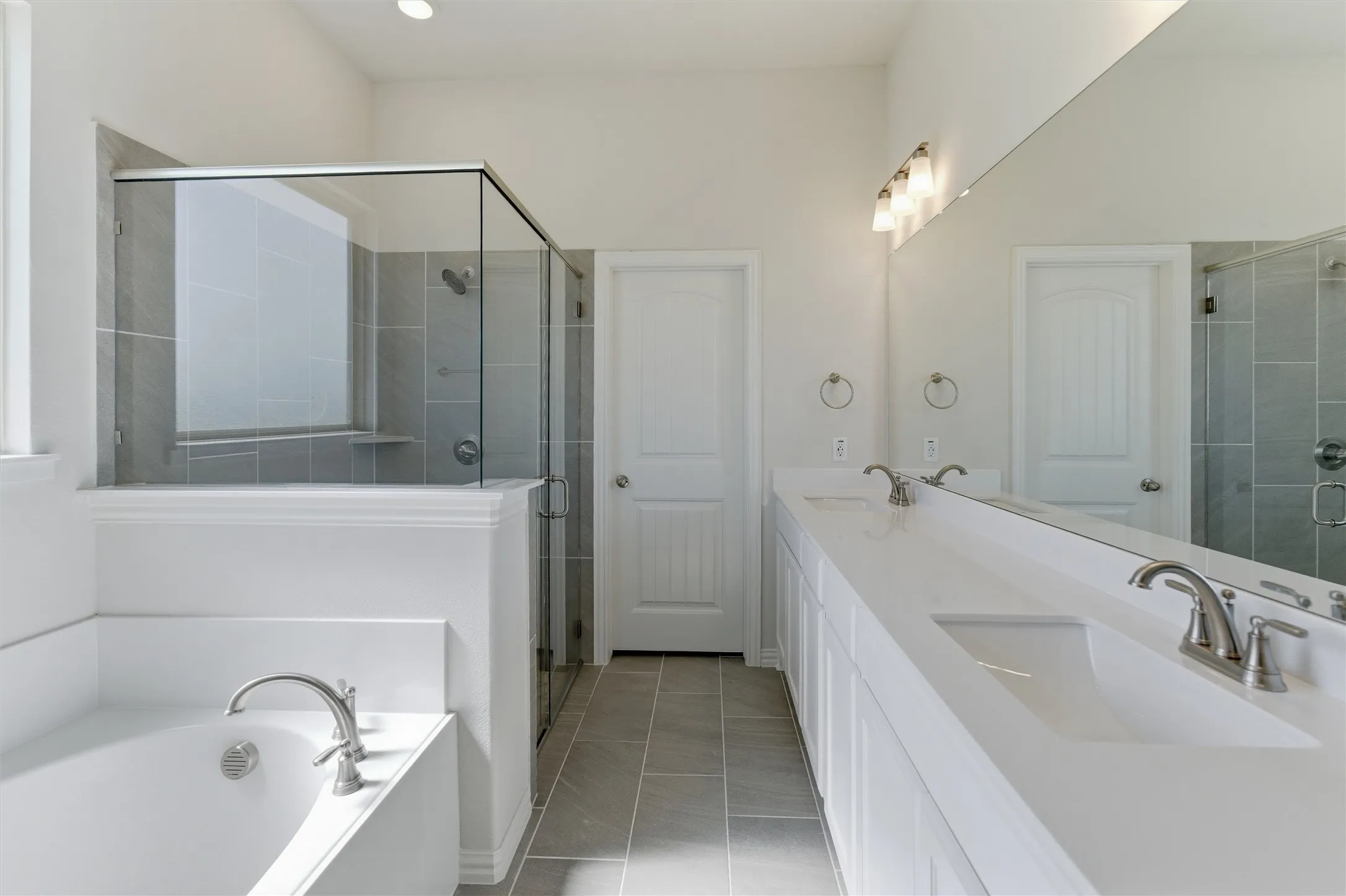 Contemporary bathroom featuring a spacious walk-in shower with glass enclosure and tiled walls, a separate soaking tub, a dual vanity with integrated sinks and brushed nickel faucets, and coordinating floor tiling