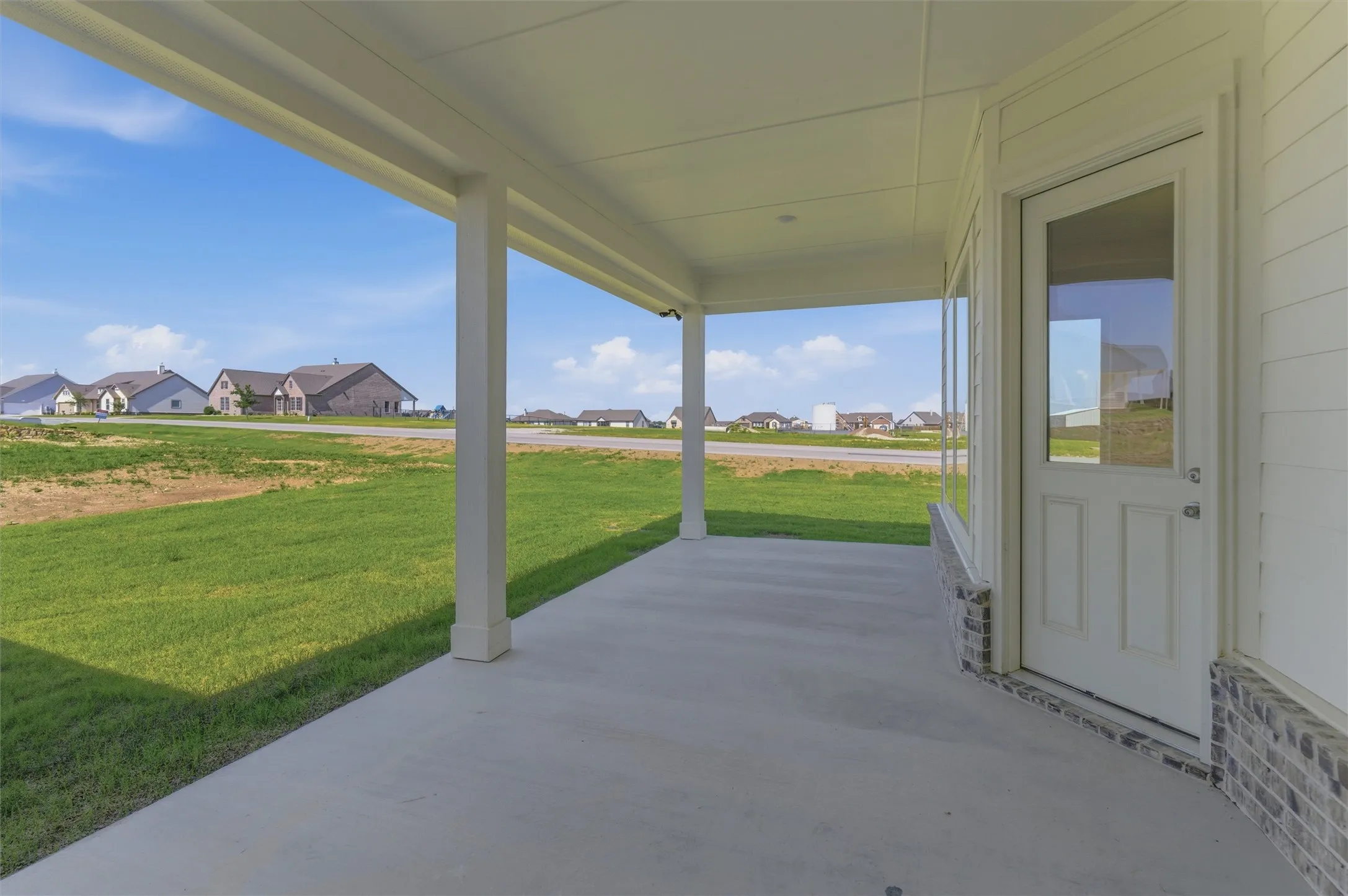 Covered concrete patio with white support columns