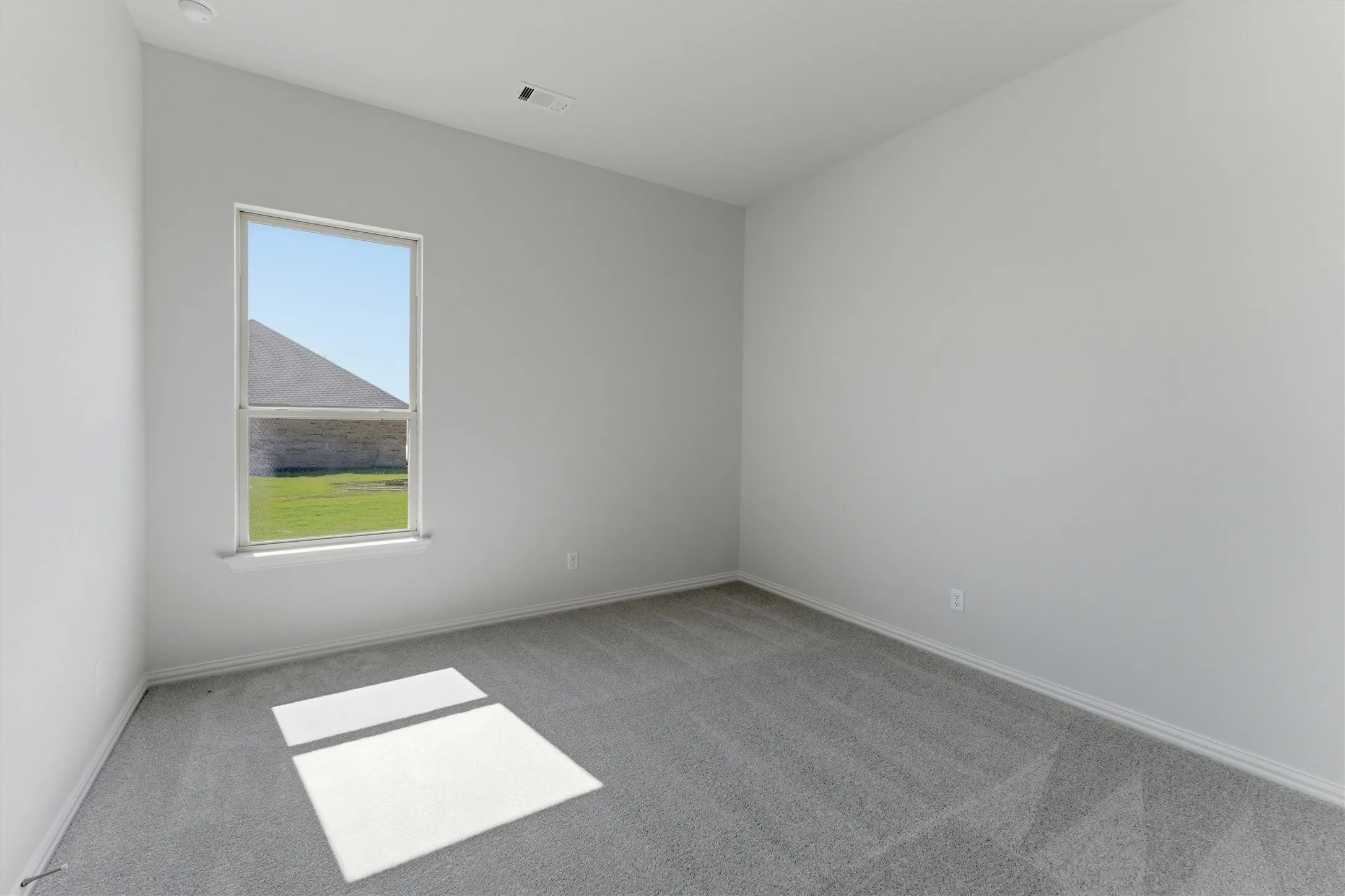 Interior space featuring light gray walls, gray carpeting, and white baseboards